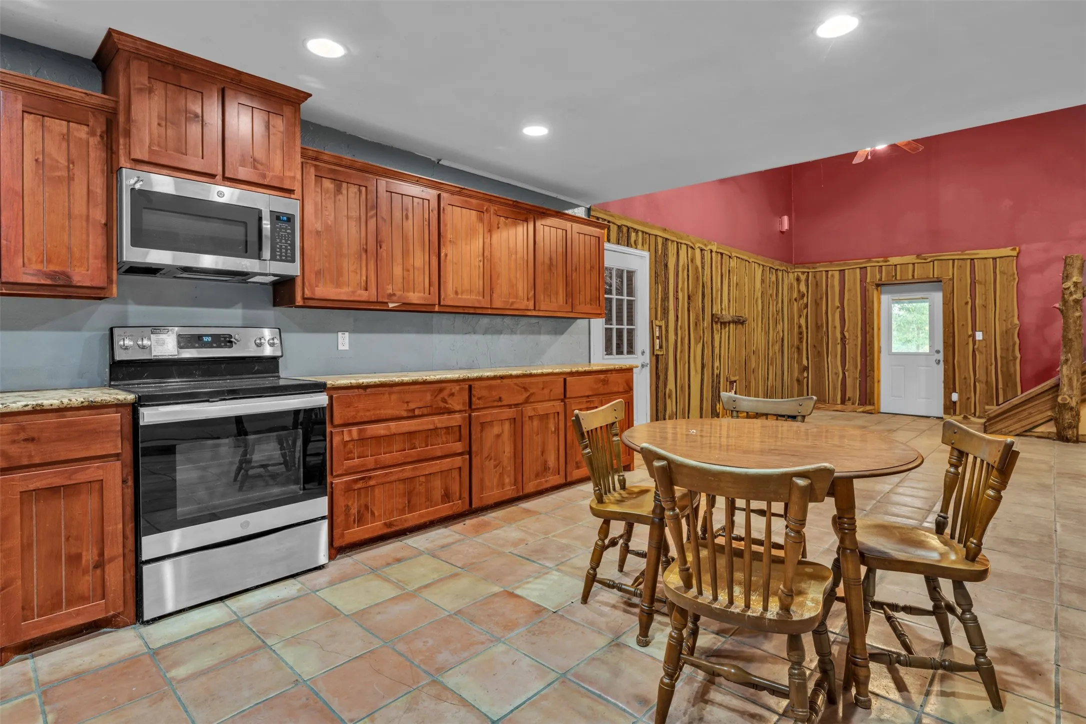 Wood cabinetry with granite countertops, stainless steel appliances, and tiled flooring