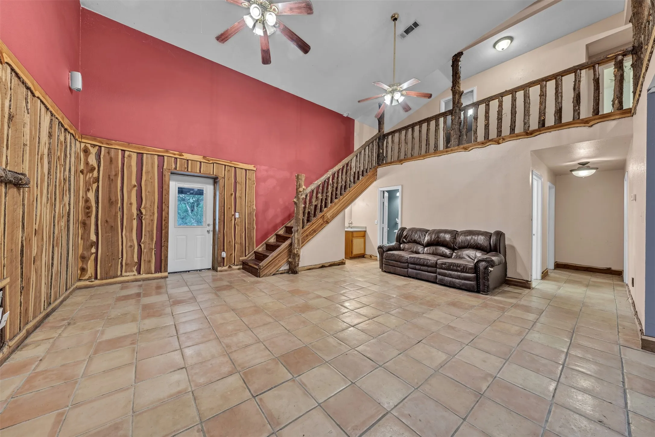 High ceilings, wood paneling, tile flooring, wood staircase, and a wood railing overlooking the living space