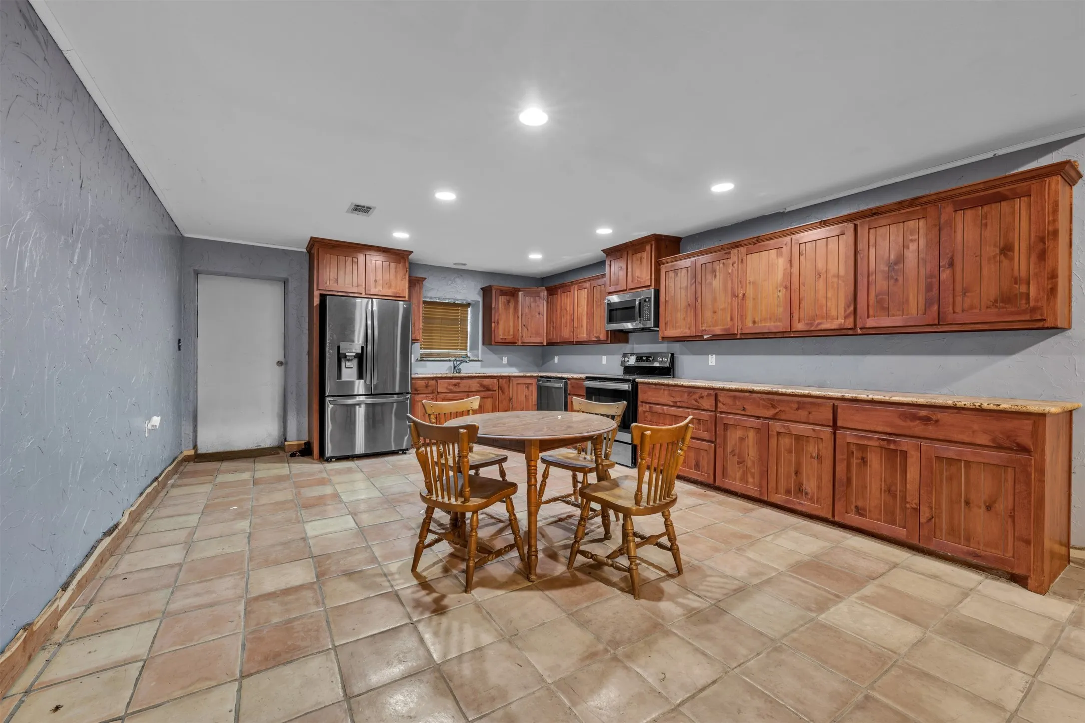 Kitchen featuring an abundance of wood-finish cabinetry, tile flooring, recessed lighting, and built-in stainless steel appliances