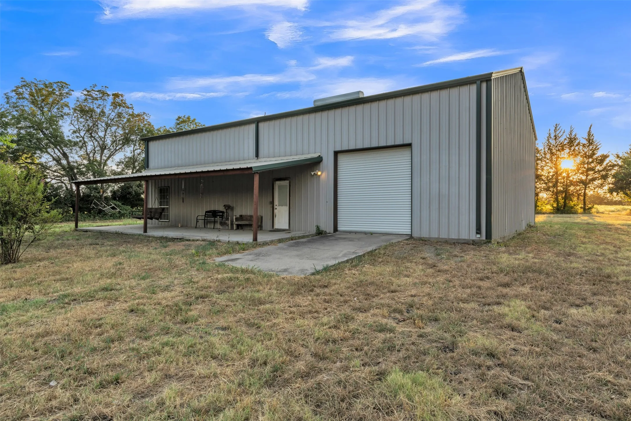 Metal construction building with an attached covered porch and a roll-up garage door