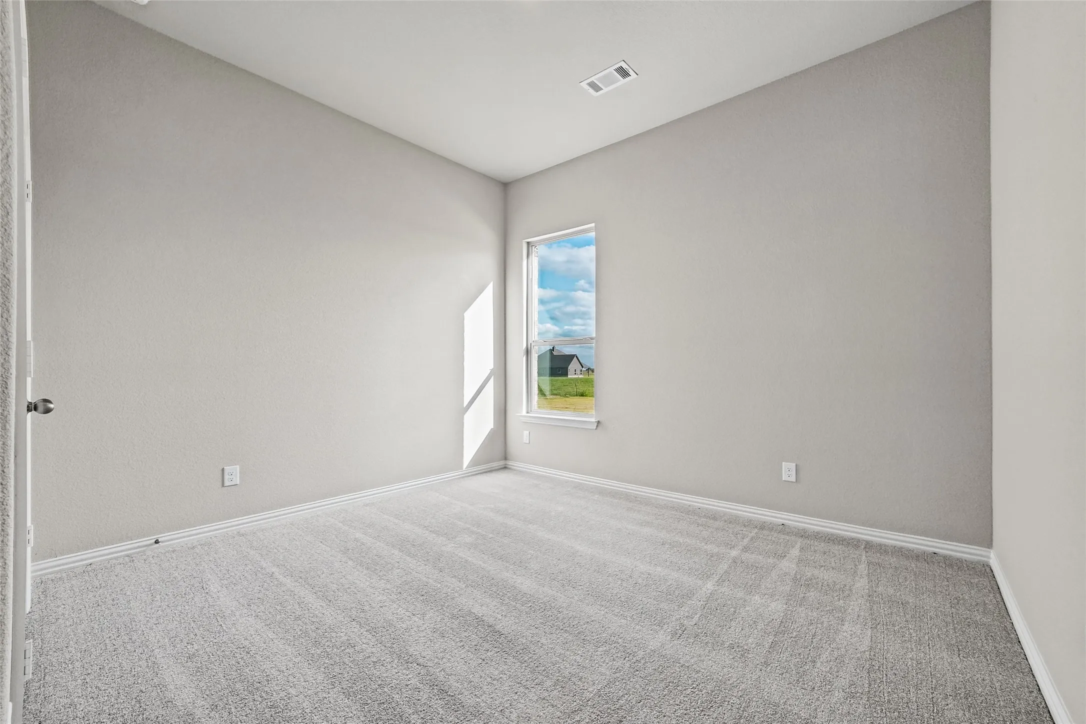 Neutral wall tones, plush wall-to-wall carpeting, and a vertical window providing natural light