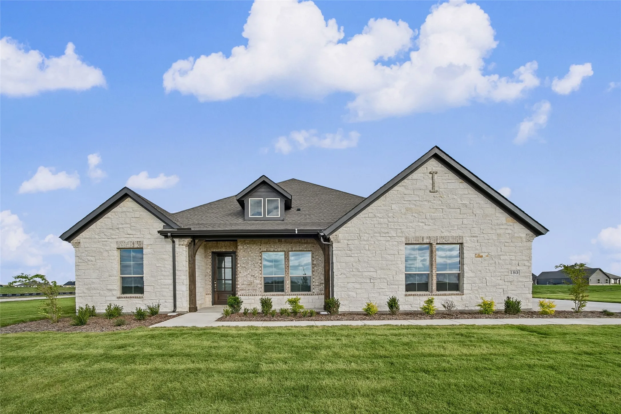Elegant stone exterior with gabled roofline and dormer accents, complemented by dark trim and professional landscaping