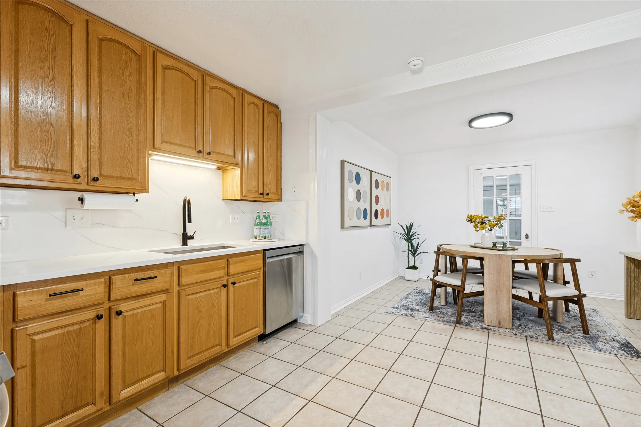 Kitchen featuring wood cabinetry, white countertops, a stainless steel dishwasher, and a black faucet