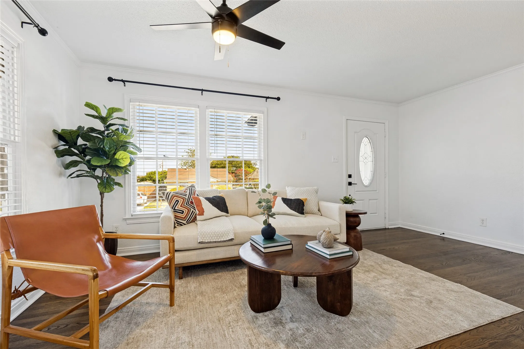 Bright living area featuring wood-finish flooring, white walls, and a ceiling fan