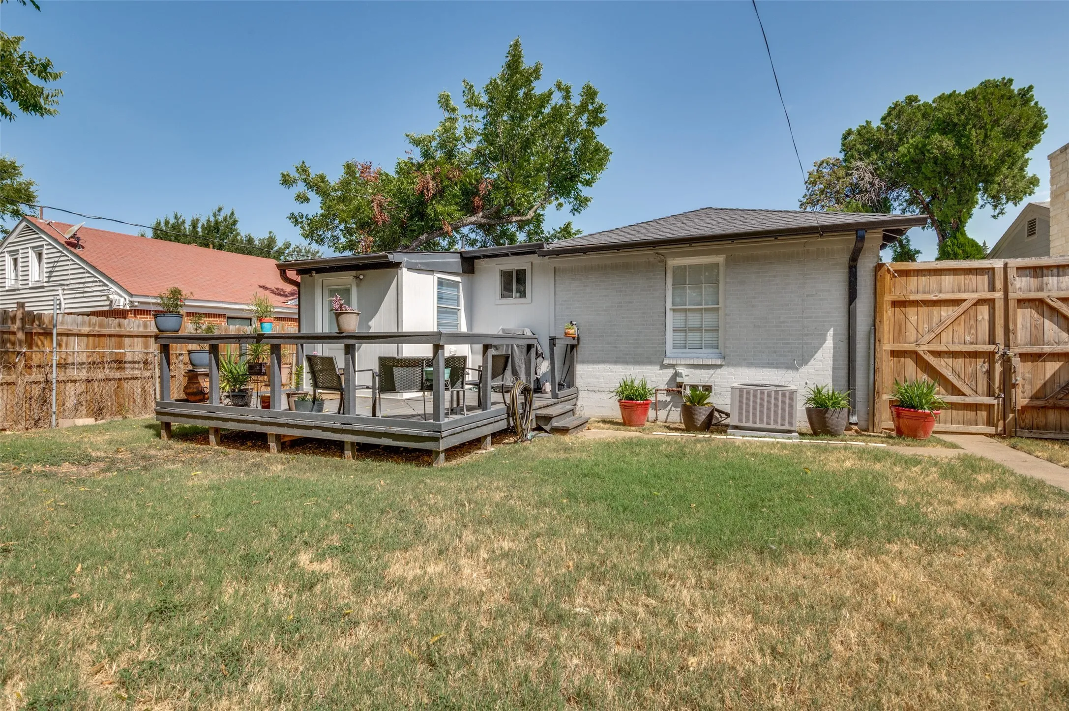 Expansive backyard featuring a wood deck, wood privacy fencing, and a paved walkway