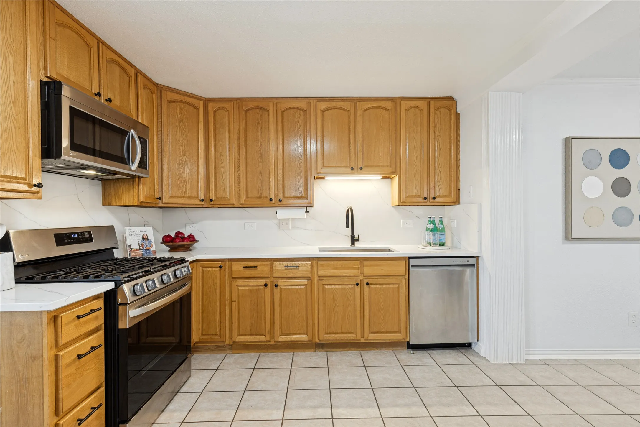 Kitchen featuring wood cabinetry, stainless steel appliances, white countertops, and a tile floor