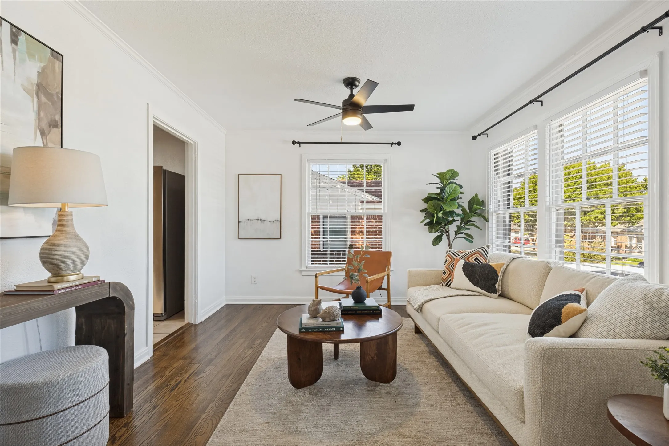 Hardwood flooring, multiple windows with blinds, ceiling fan with light, and crown molding