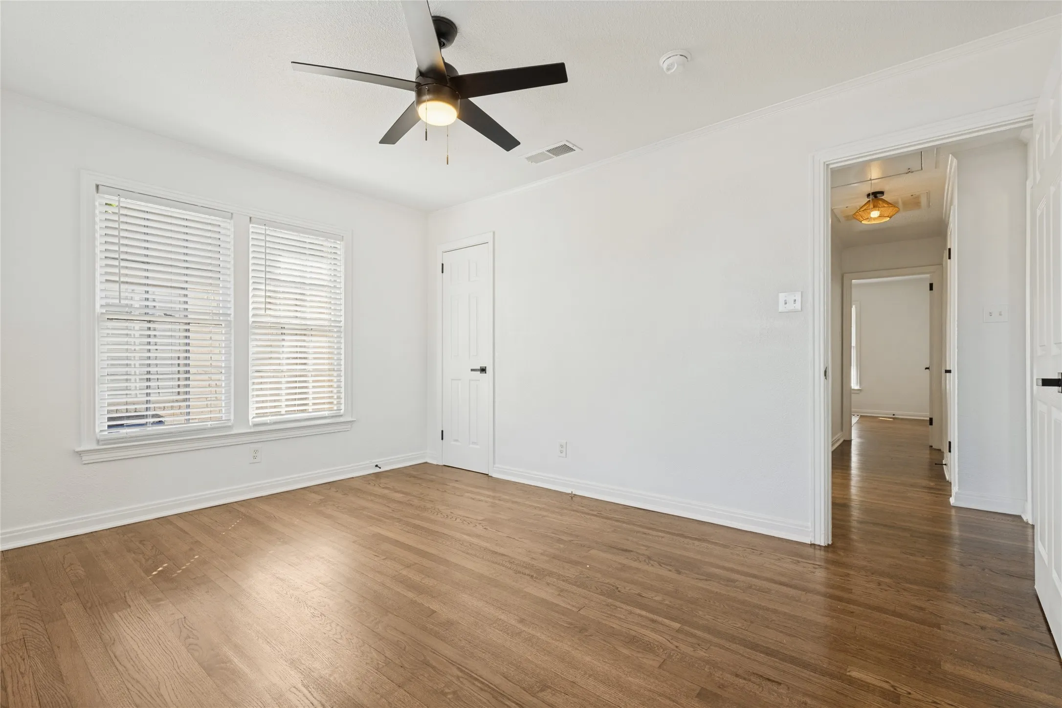 Hardwood-style flooring with white walls and trim, featuring a ceiling fan with integrated lighting