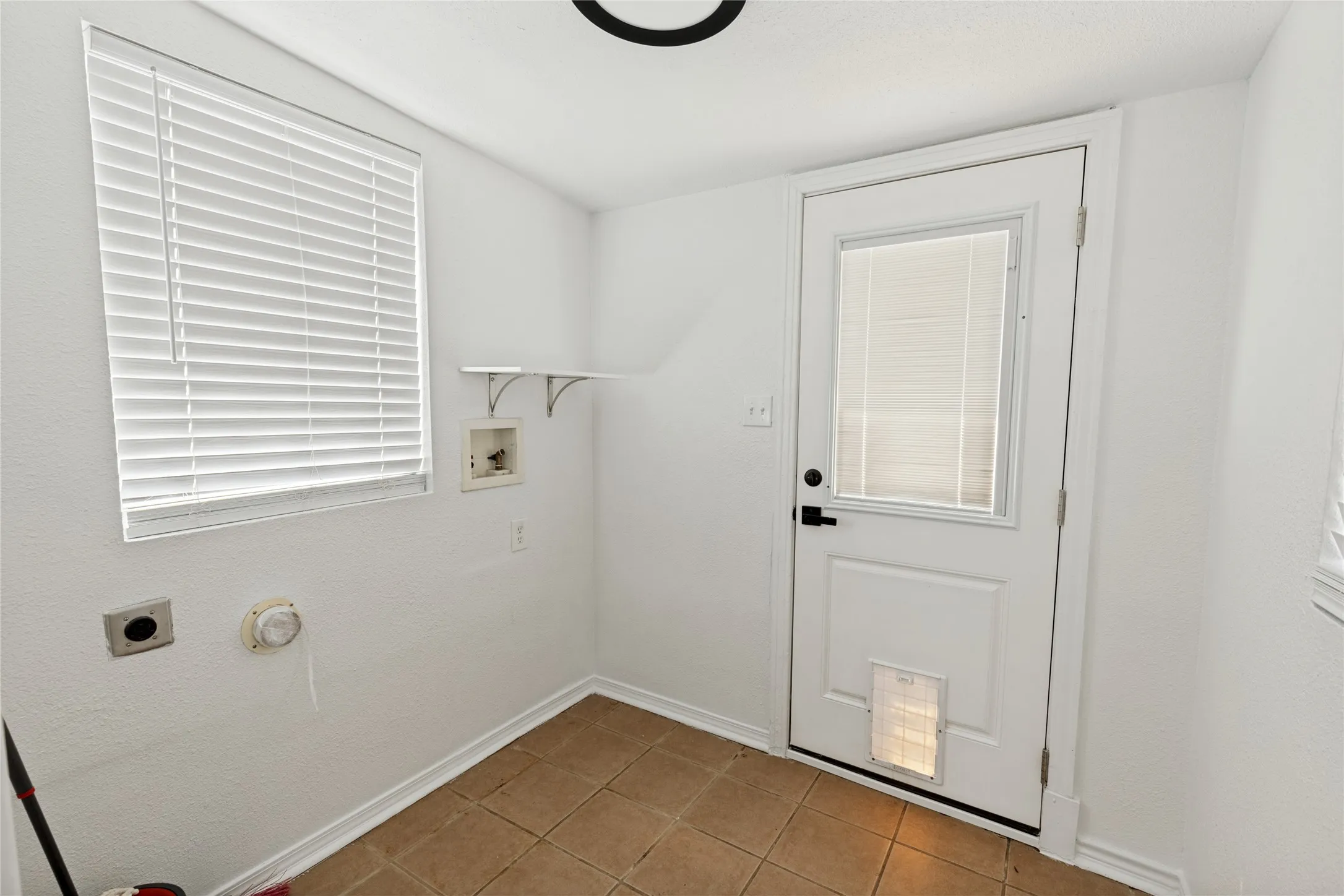 Tiled flooring with white walls and a window featuring horizontal blinds