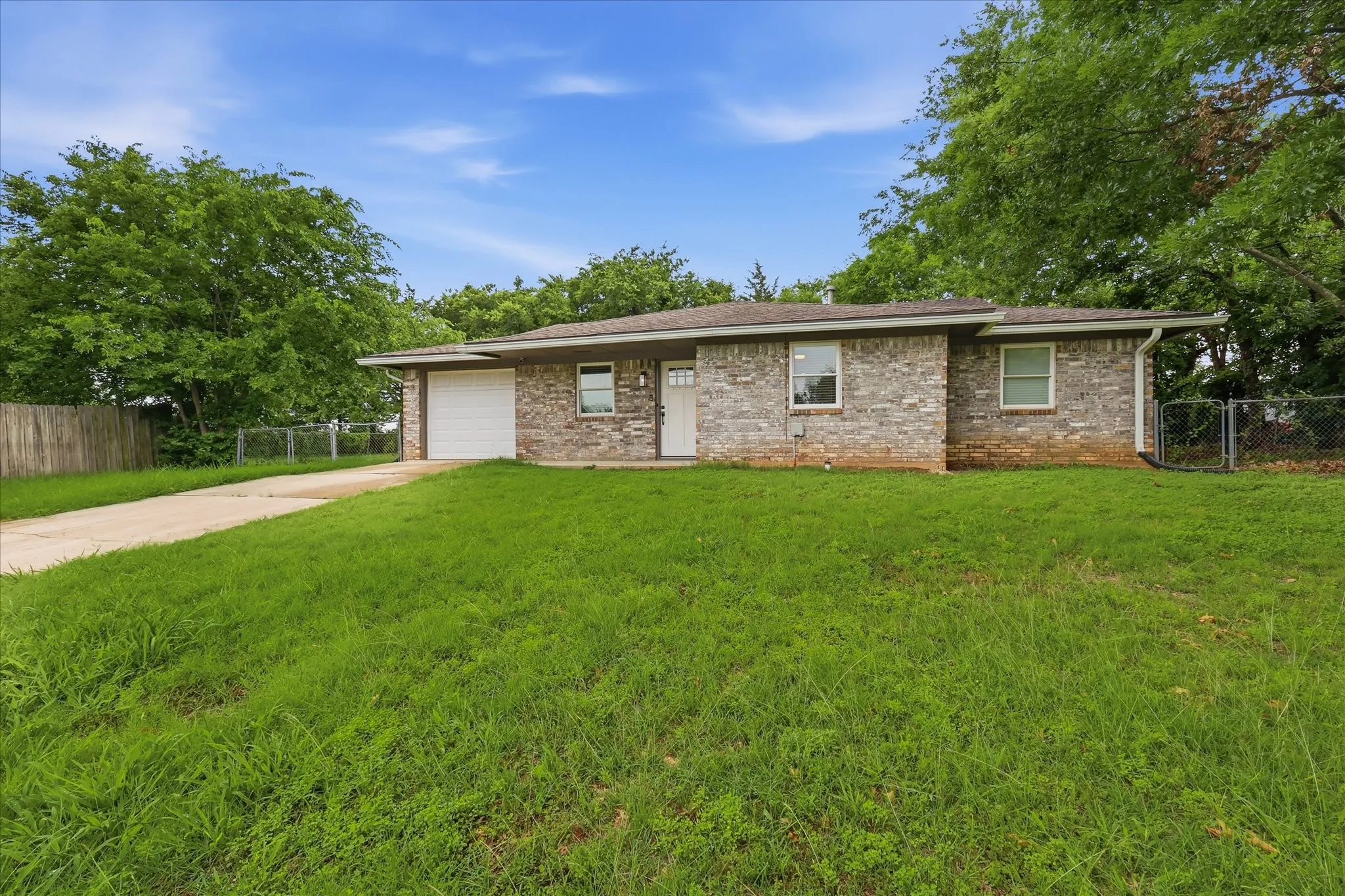 Brick exterior with an attached garage, white entry door, and a concrete driveway