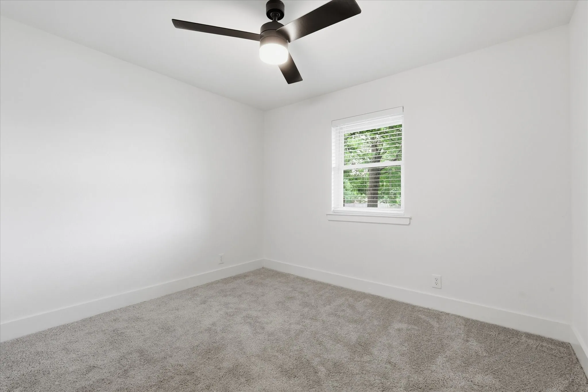 Neutral wall tones with a ceiling fan, window with blinds, and carpet flooring
