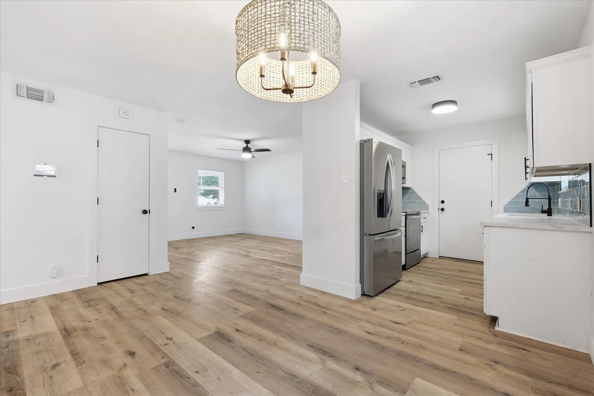 Open-concept living area with wood-finish flooring, white walls, and a decorative chandelier
