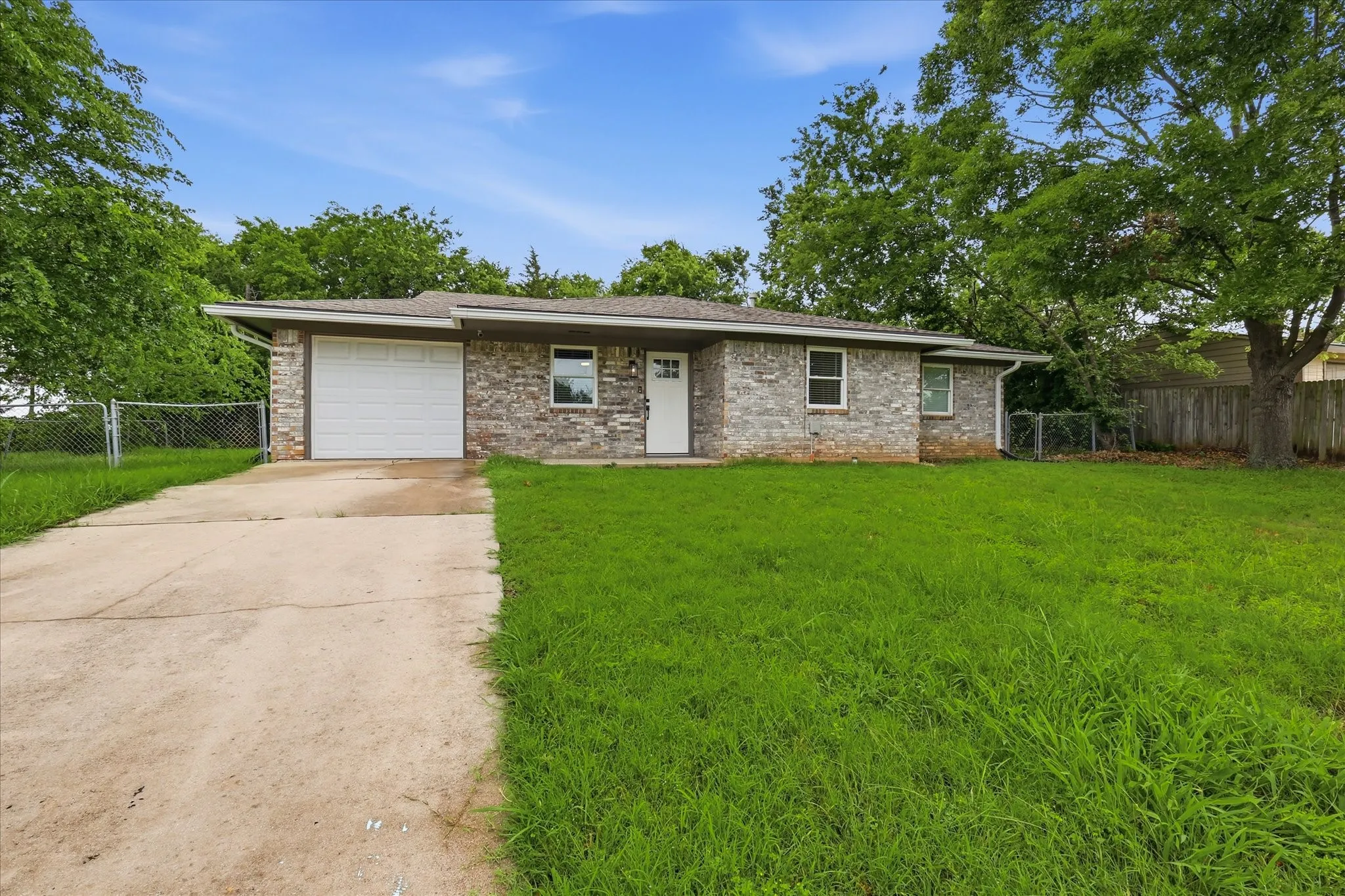 Stone veneer exterior with a single-car garage, concrete driveway, and established front yard