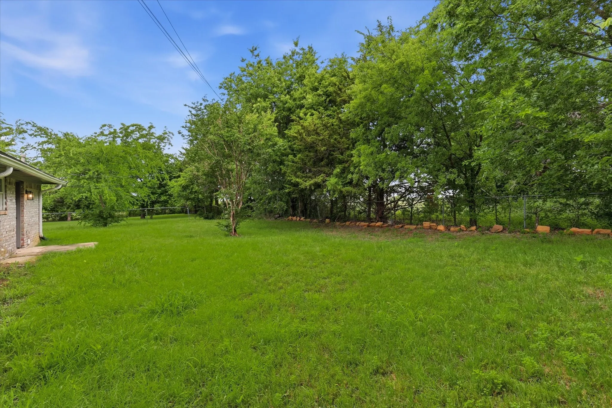 Expansive grassy area with mature trees and a stone retaining wall