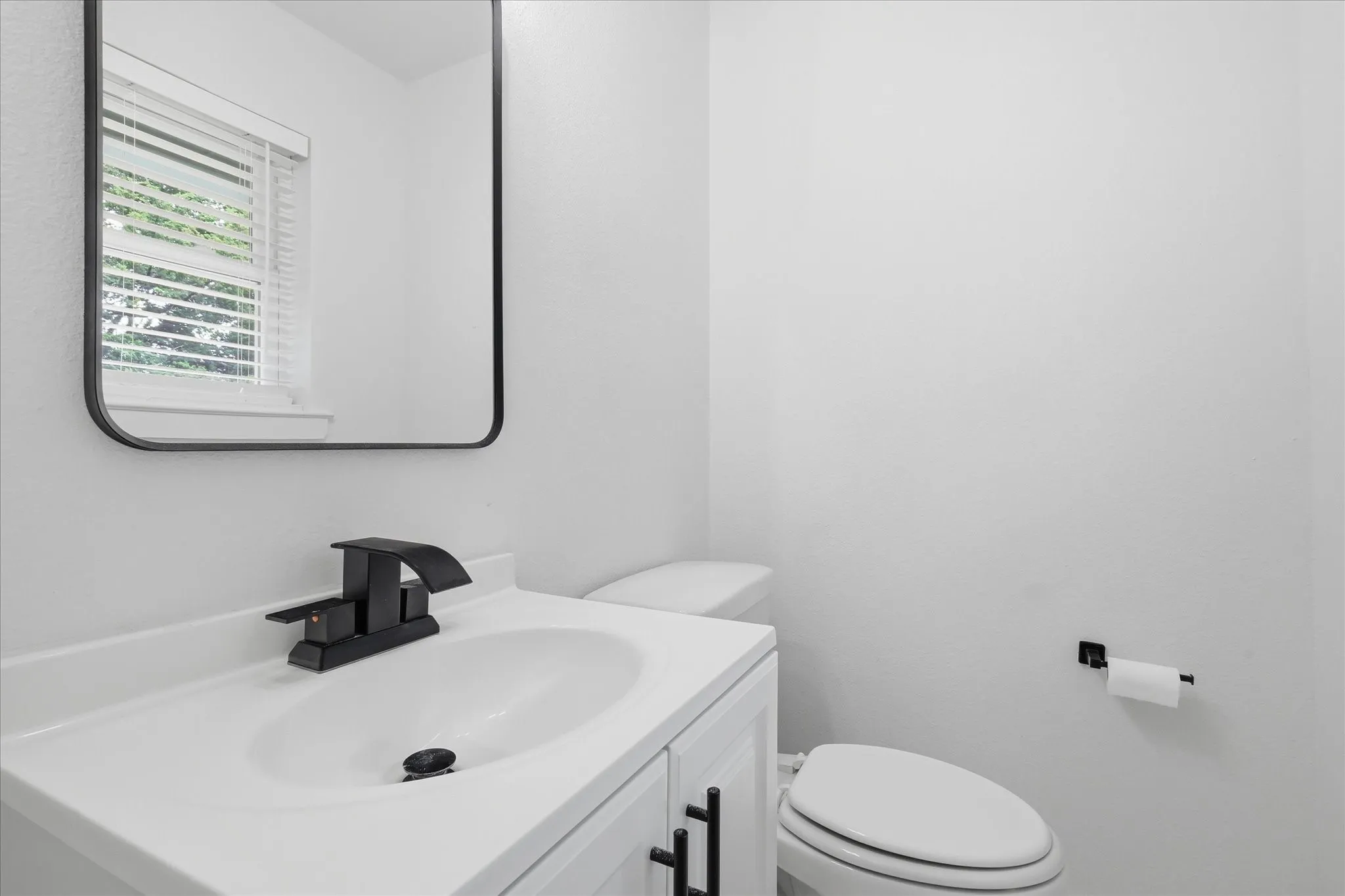 White vanity with a single-basin sink, matte black faucet, and coordinating hardware