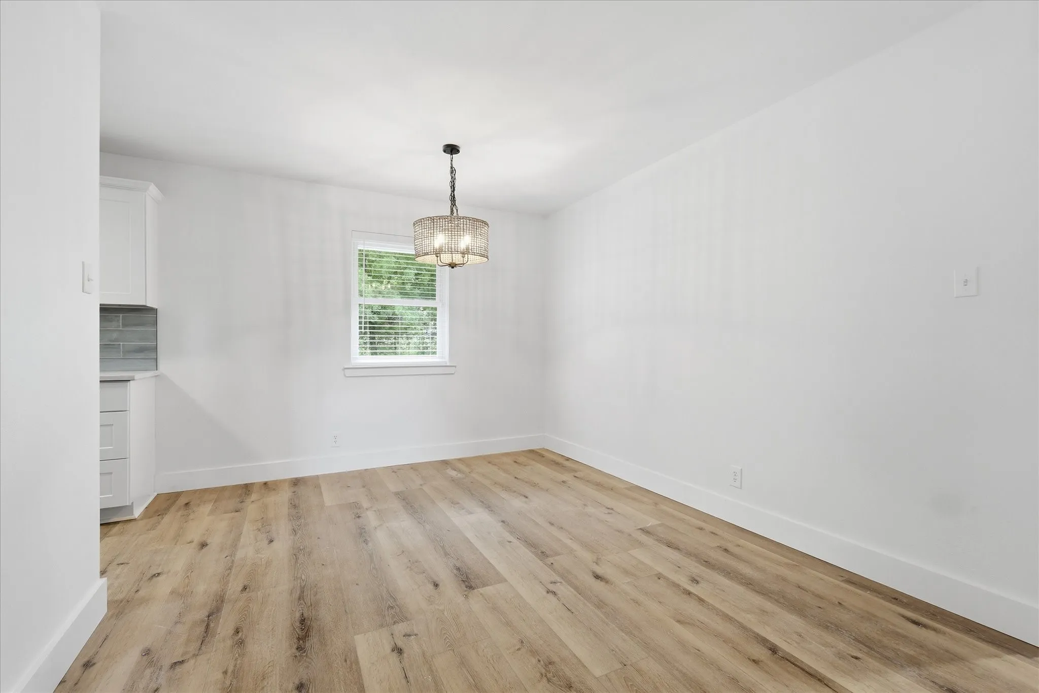 Wood-finish flooring, white walls, and a contemporary chandelier