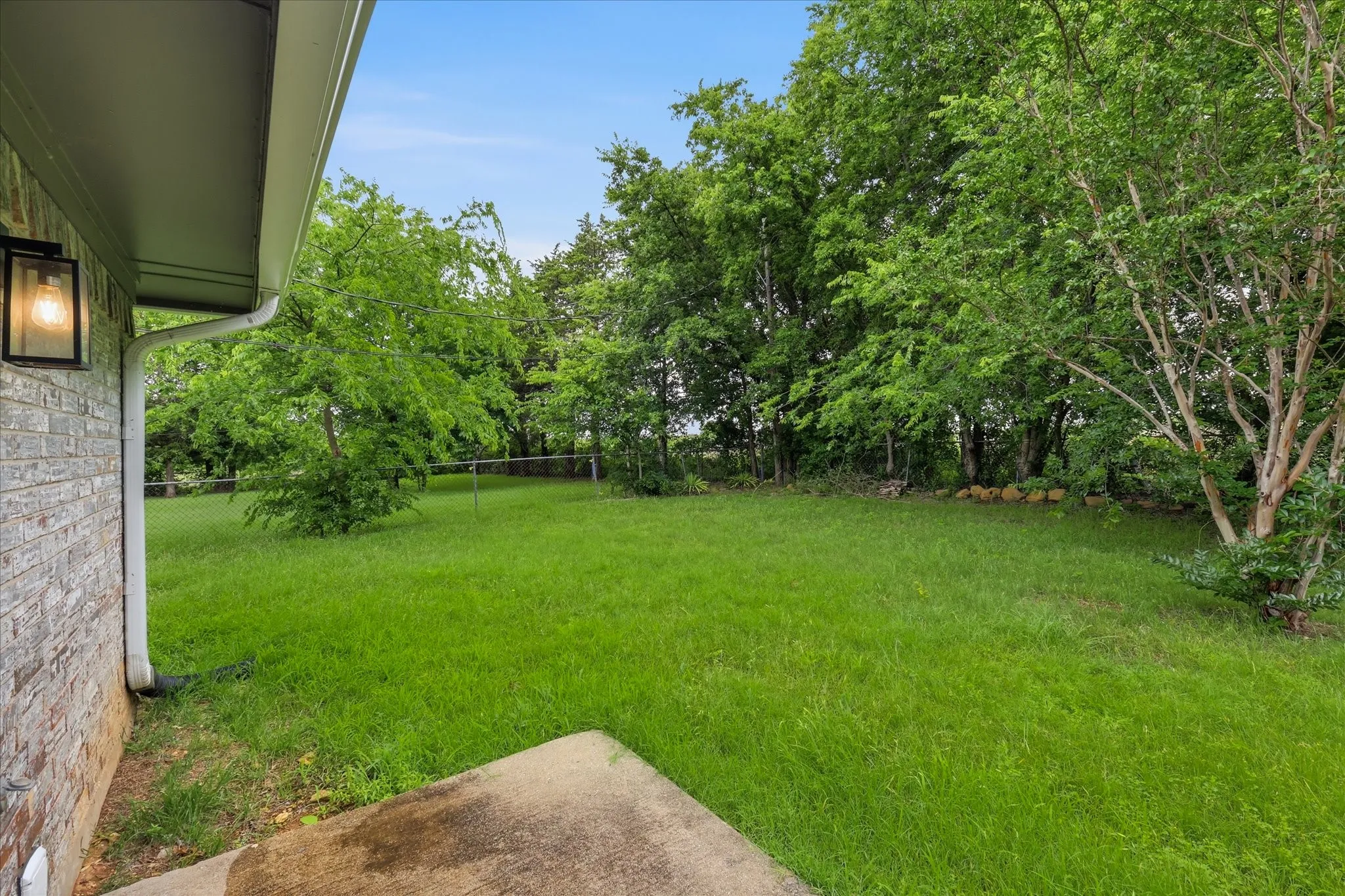 Expansive lawn area with mature trees and a concrete patio section