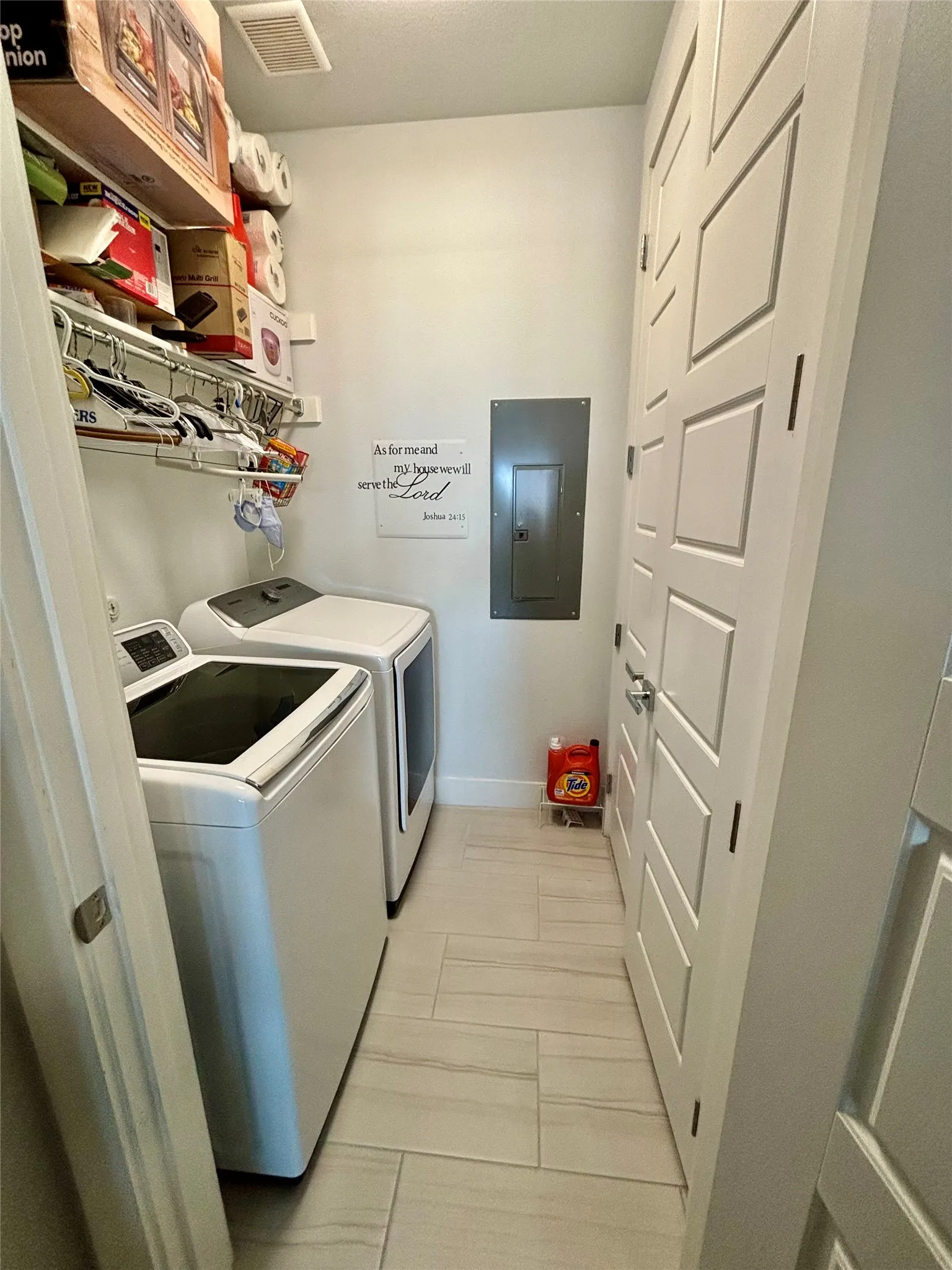 Laundry area featuring light-toned tile flooring, built-in shelving, and white paneled doors