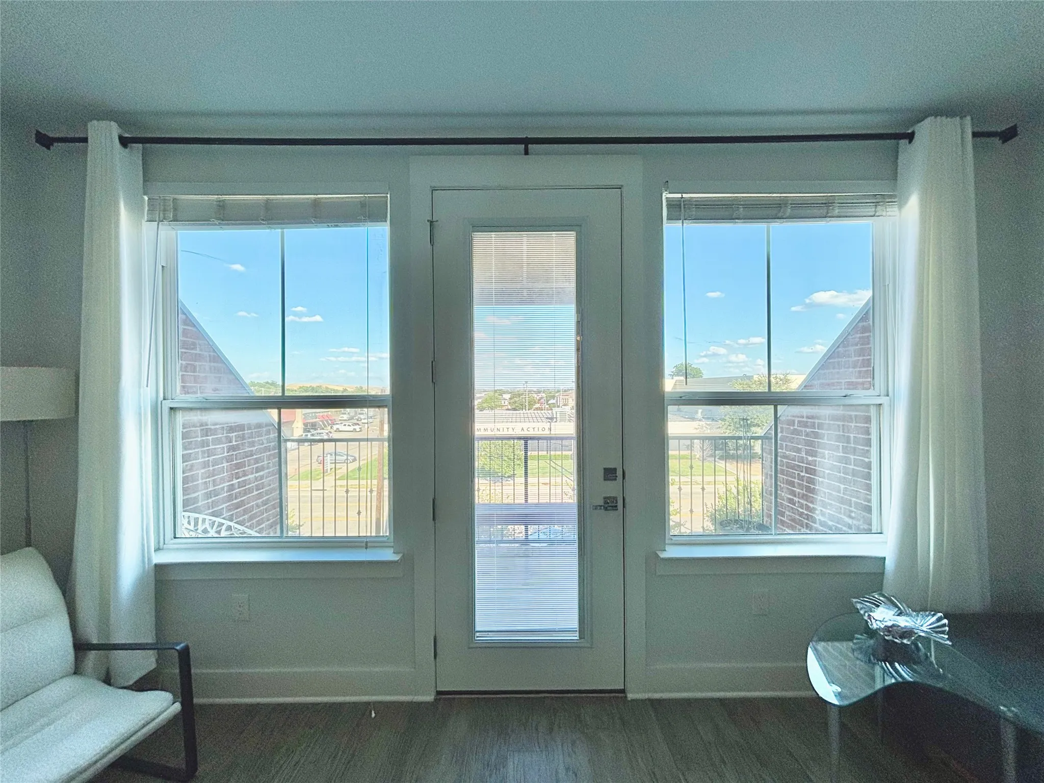 Wood-finish flooring with a balcony access door flanked by two windows