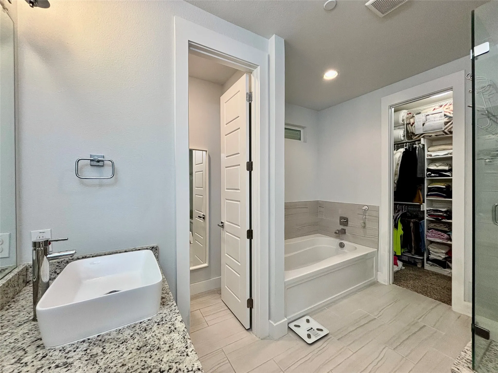 Bathroom featuring a rectangular vessel sink, granite-style countertop, built-in bathtub with tiled surround, and a glass-enclosed shower