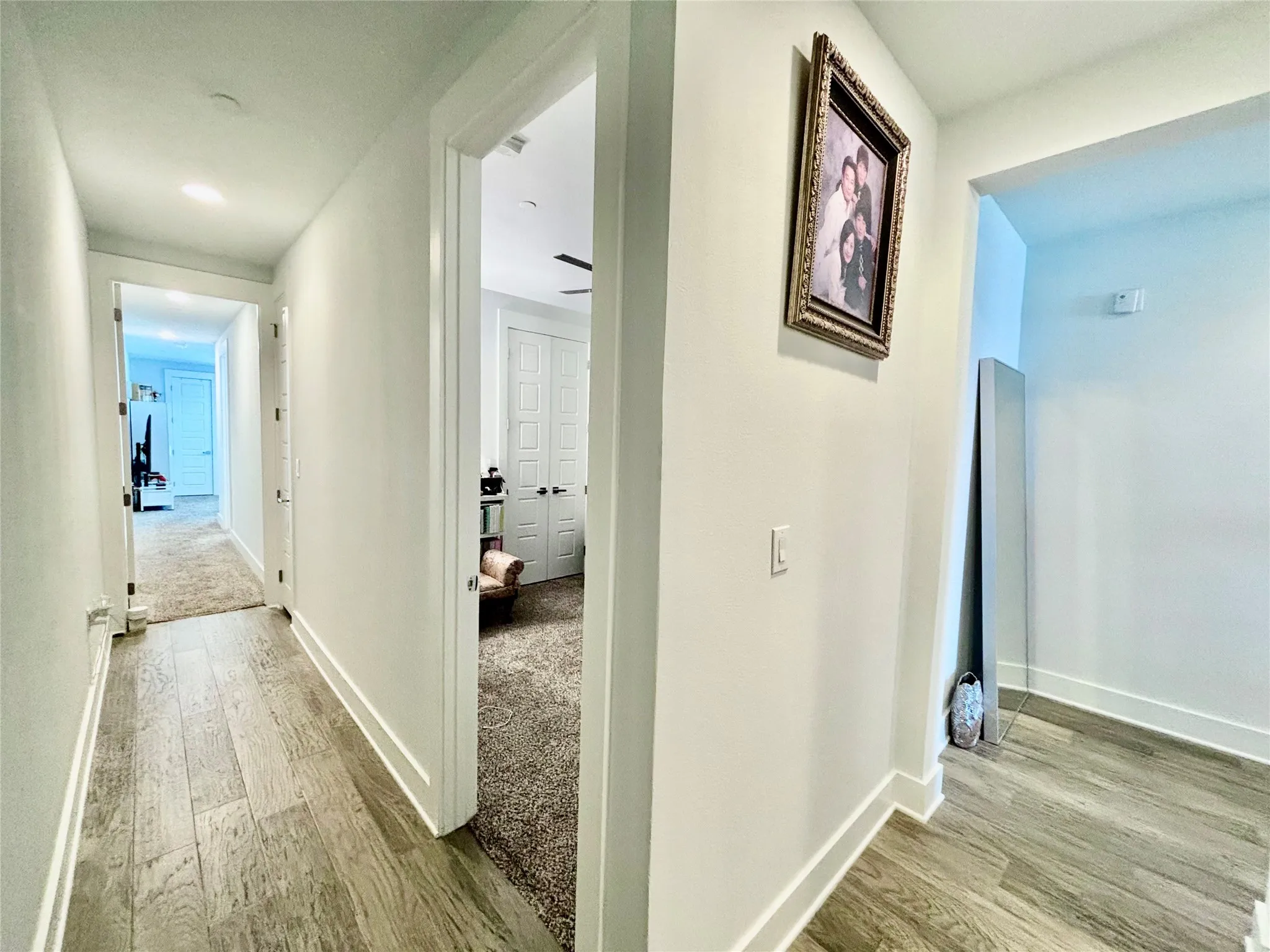 Hallway featuring wood-finish flooring, recessed lighting, and white trim
