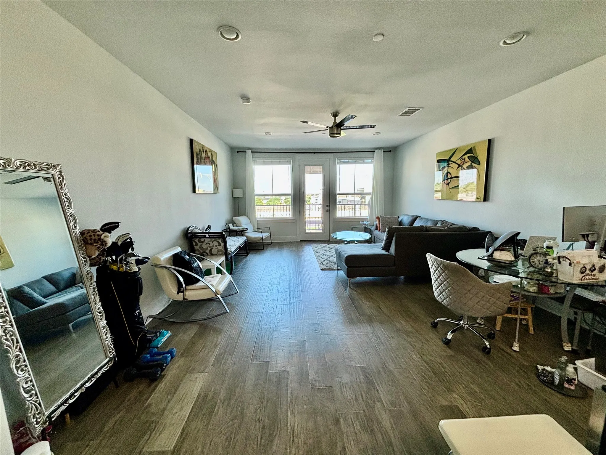 Wood-finish flooring throughout, recessed ceiling lighting, ceiling fan, and French doors leading to an exterior balcony