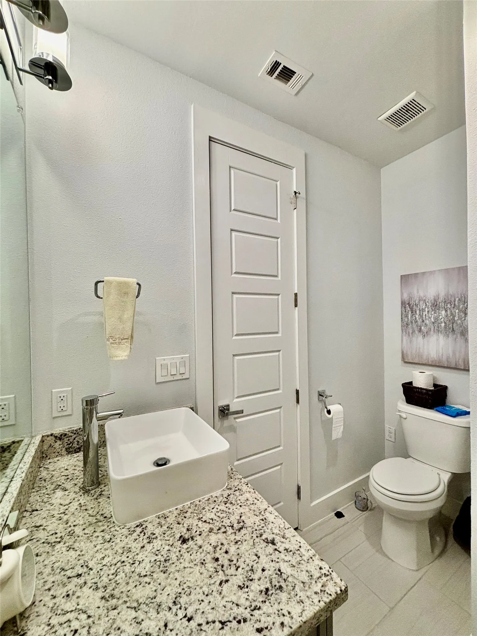 White rectangular vessel sink with a chrome faucet, granite-finish countertop, and a white paneled door