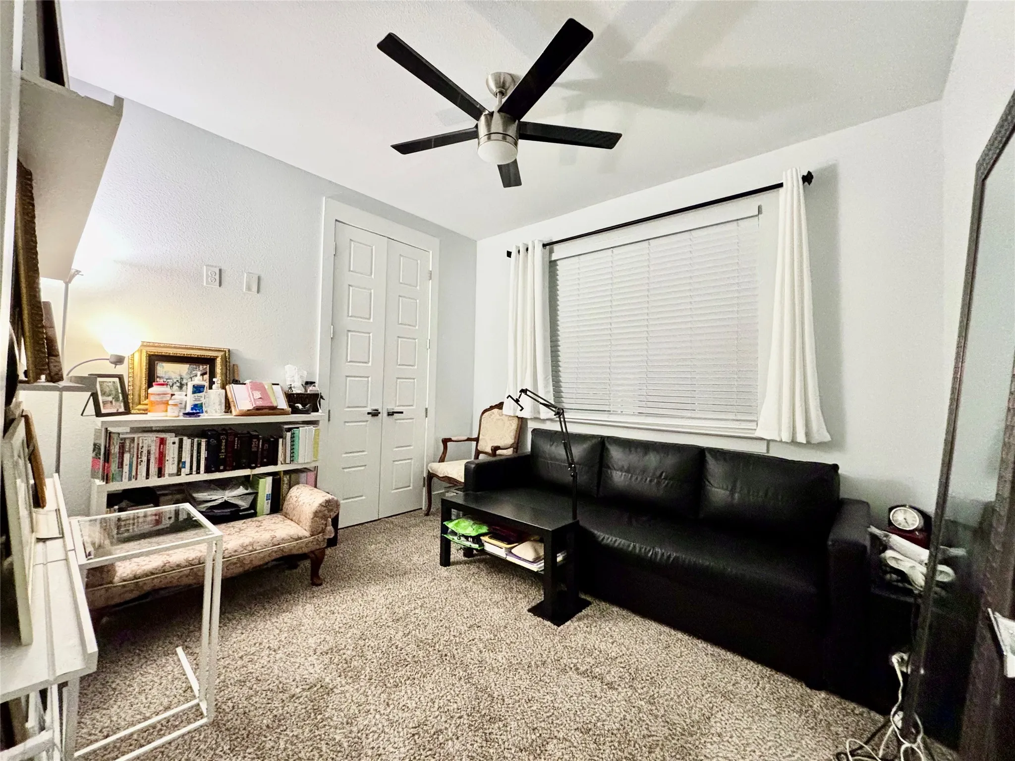 Recessed window with blinds and drapes, ceiling fan with integrated lighting, carpeted flooring, and double paneled doors