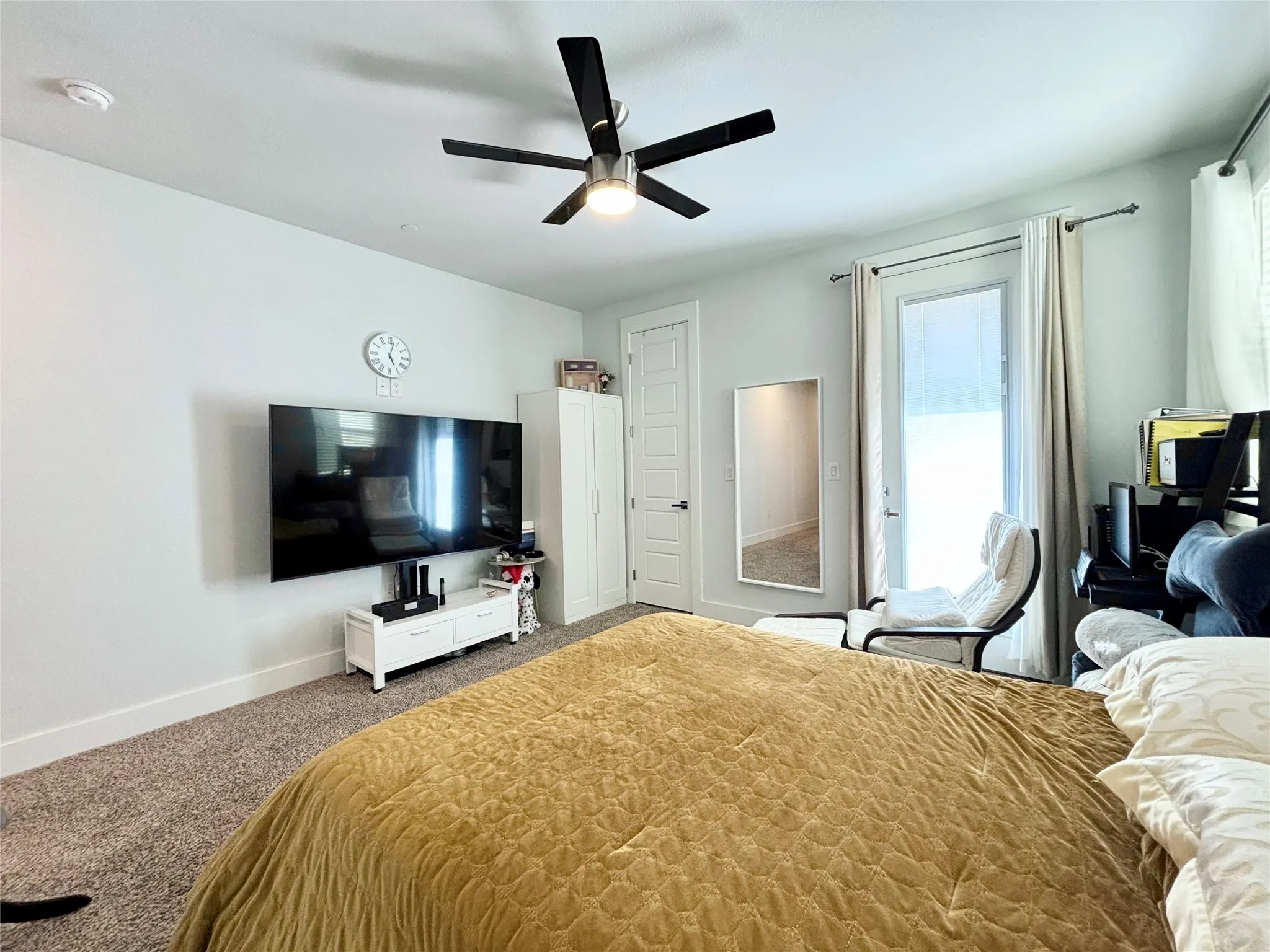 Ceiling fan with integrated lighting, a full-lite door with hardware, carpet flooring, and a white interior door with panel detailing
