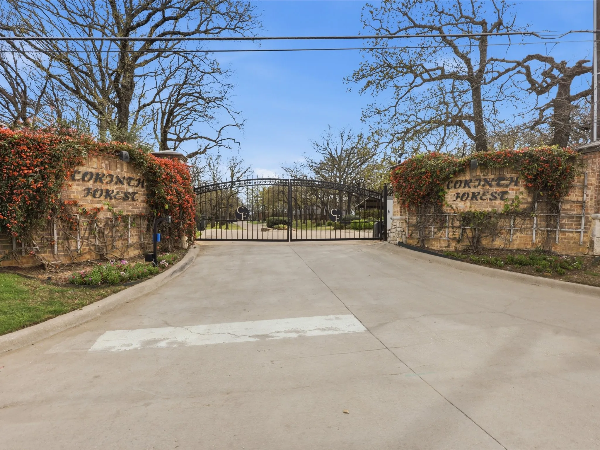Private gated communityImpressive gated entry featuring substantial brick pillars with ivy-covered stonework and decorative wrought-iron gates