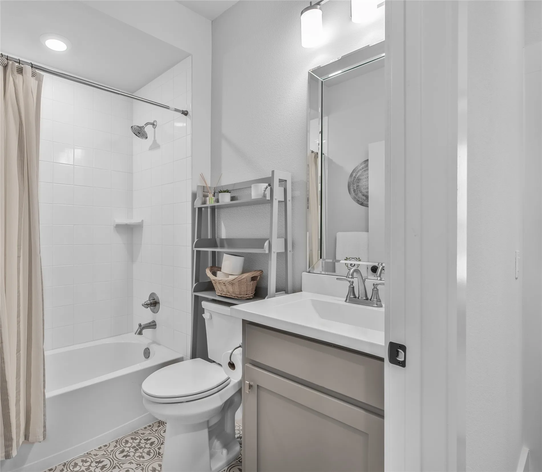 Bathroom featuring a white bathtub with tile surround, a built-in vanity with light-toned cabinetry, a rectangular sink, and a decorative mirror