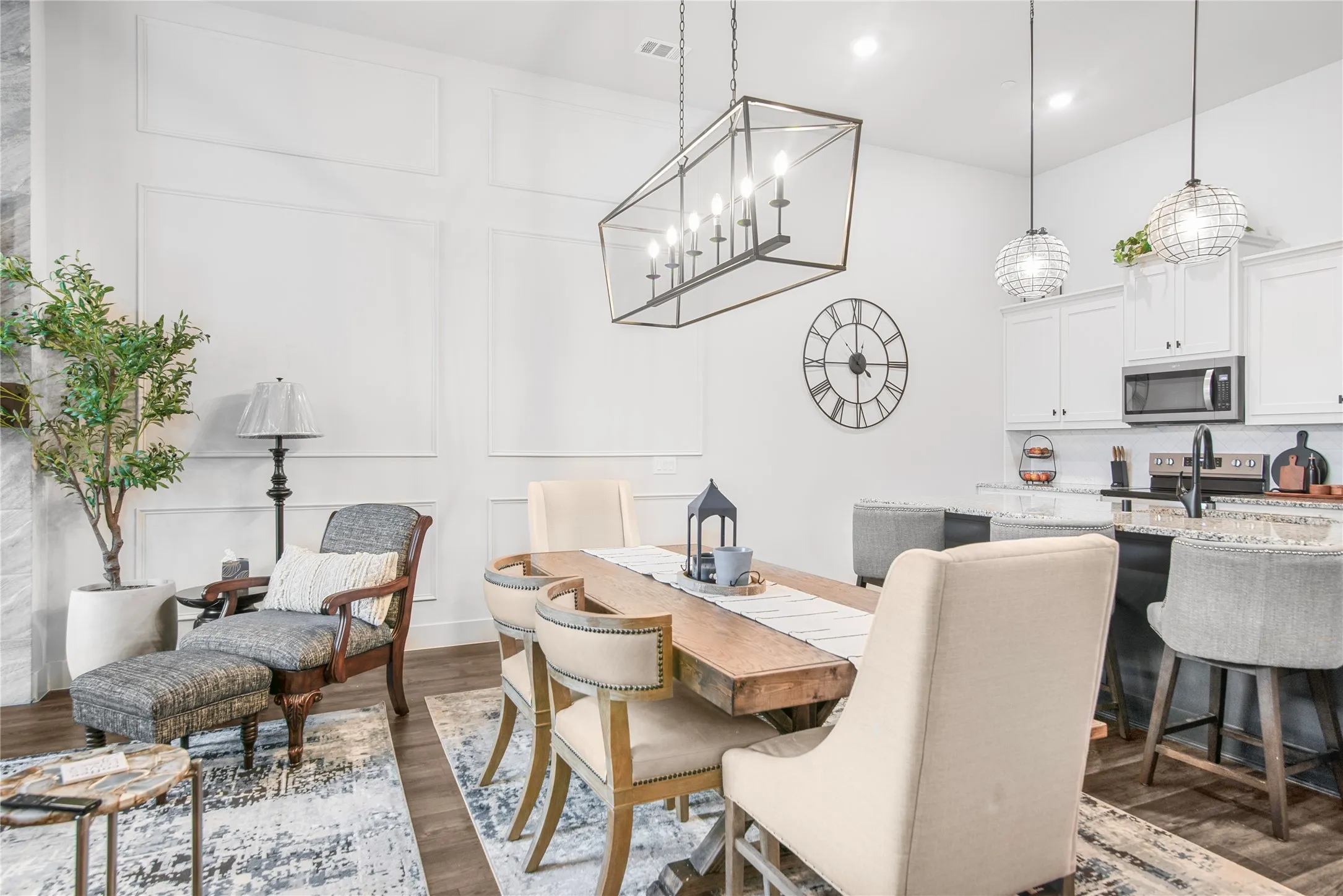 Open-concept living area with wood-finish flooring, white paneled walls, and a recessed lighting