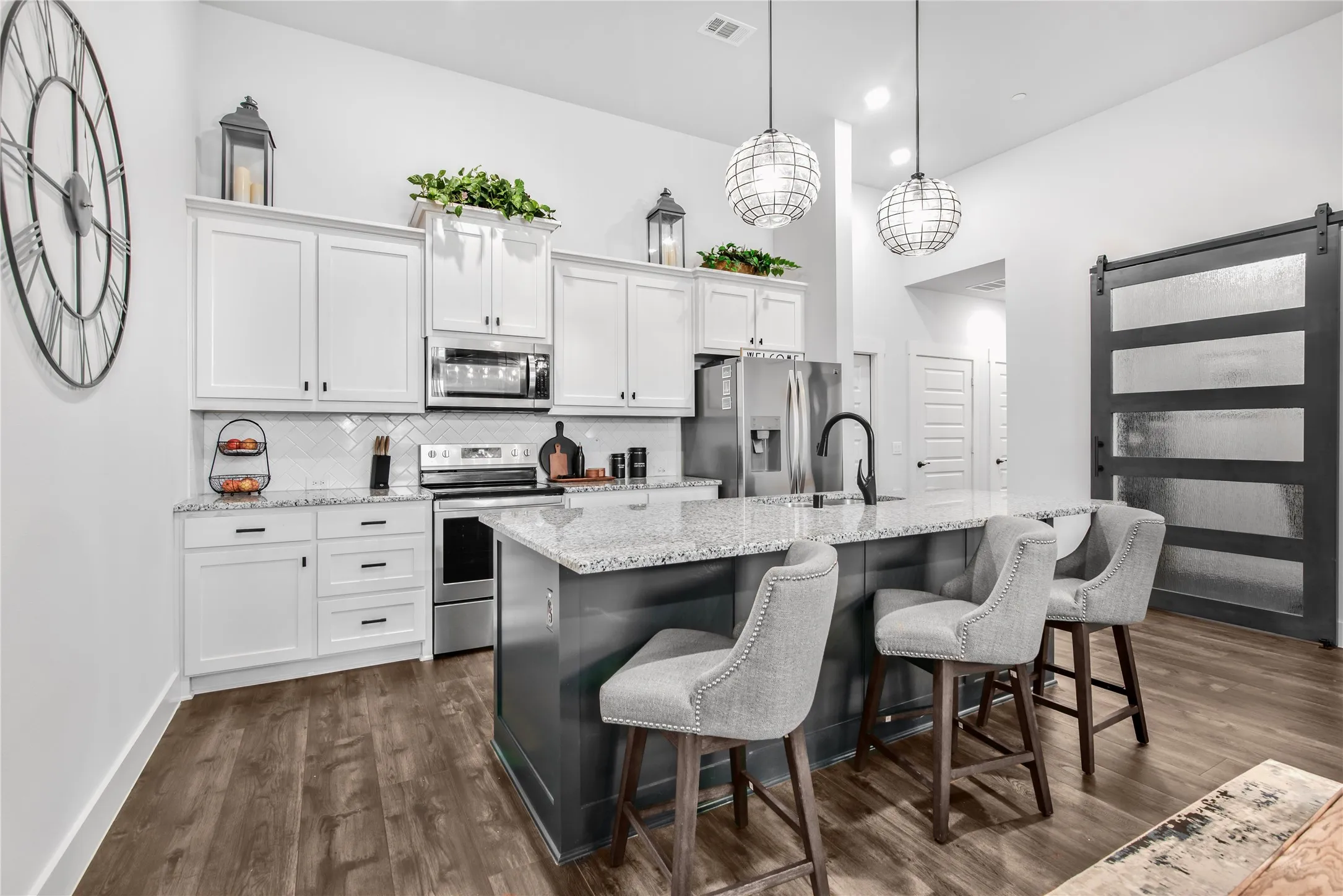 Kitchen featuring white upper and lower cabinetry, stainless steel appliances, a tile backsplash, and wood-finish flooring