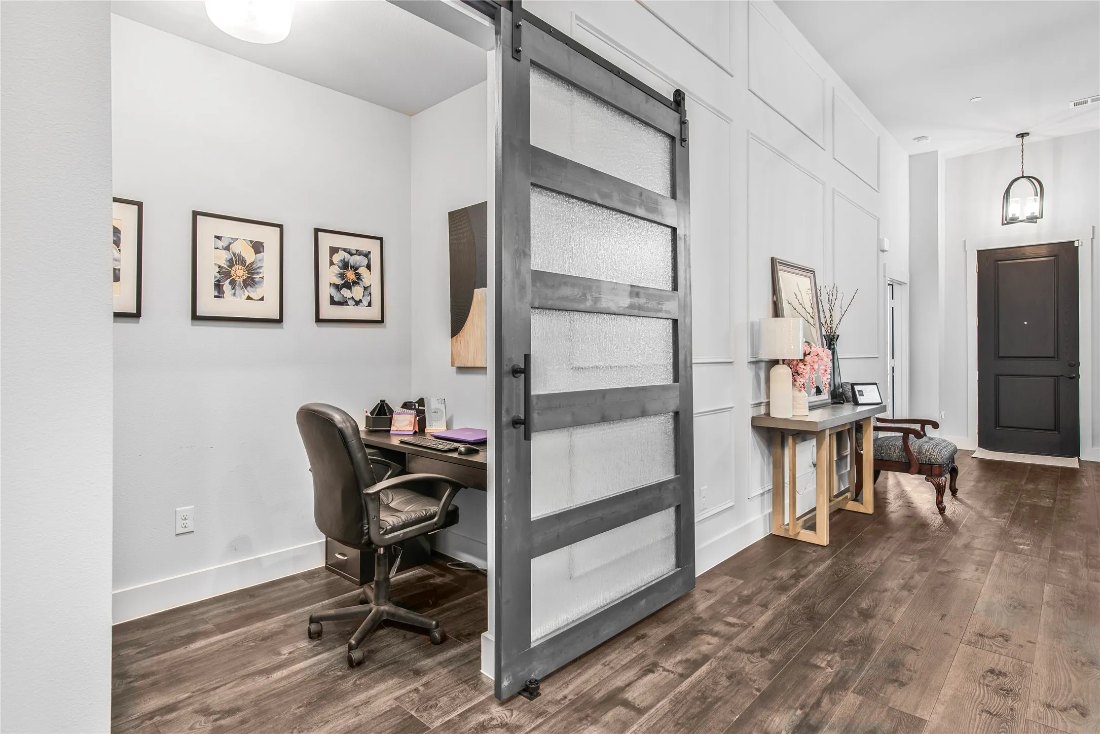 Wood-finish flooring throughout, a sliding barn door with frosted glass panels, and a paneled accent wall