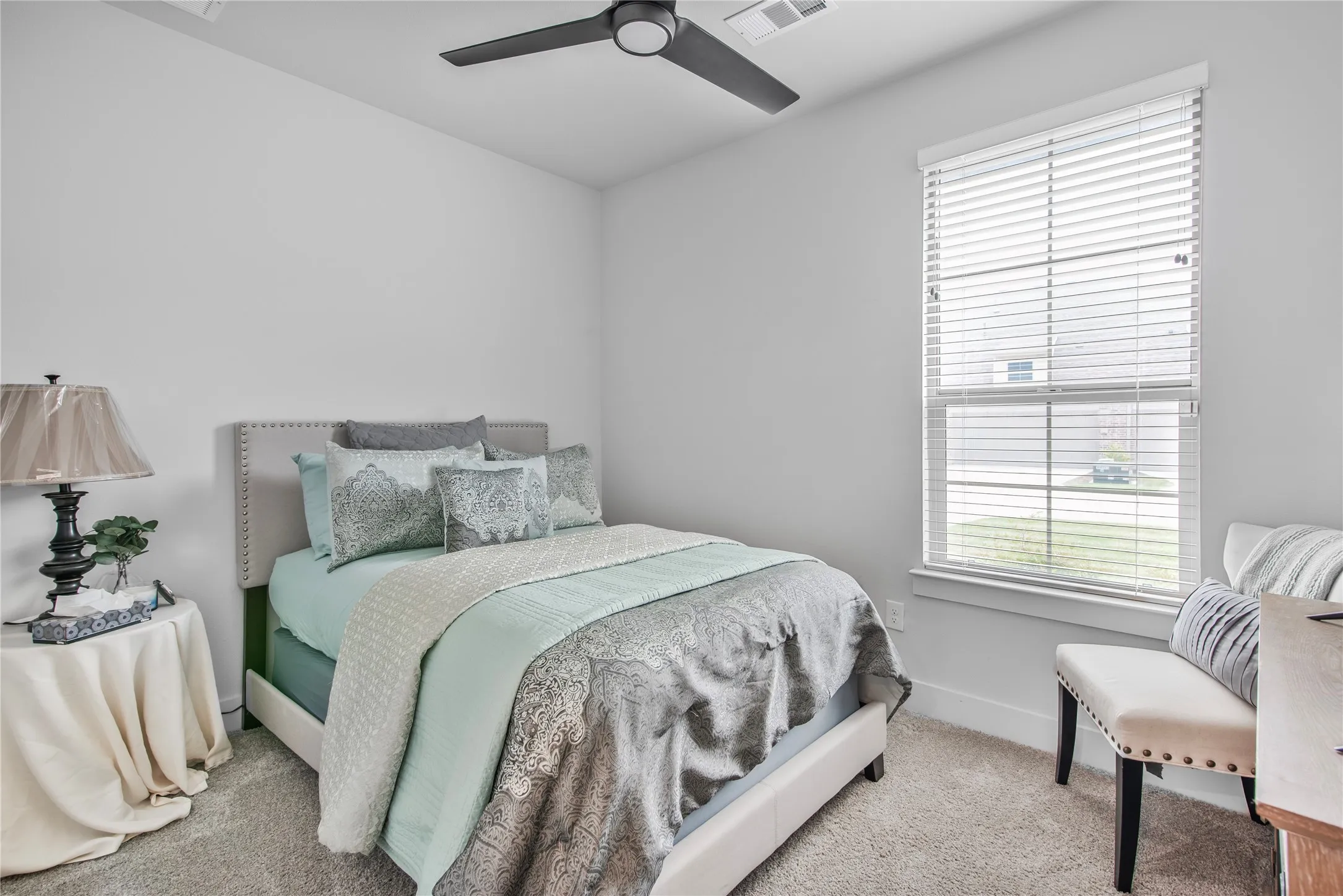 Plush carpeting, window with blinds, ceiling fan with integrated lighting, and a neutral color palette