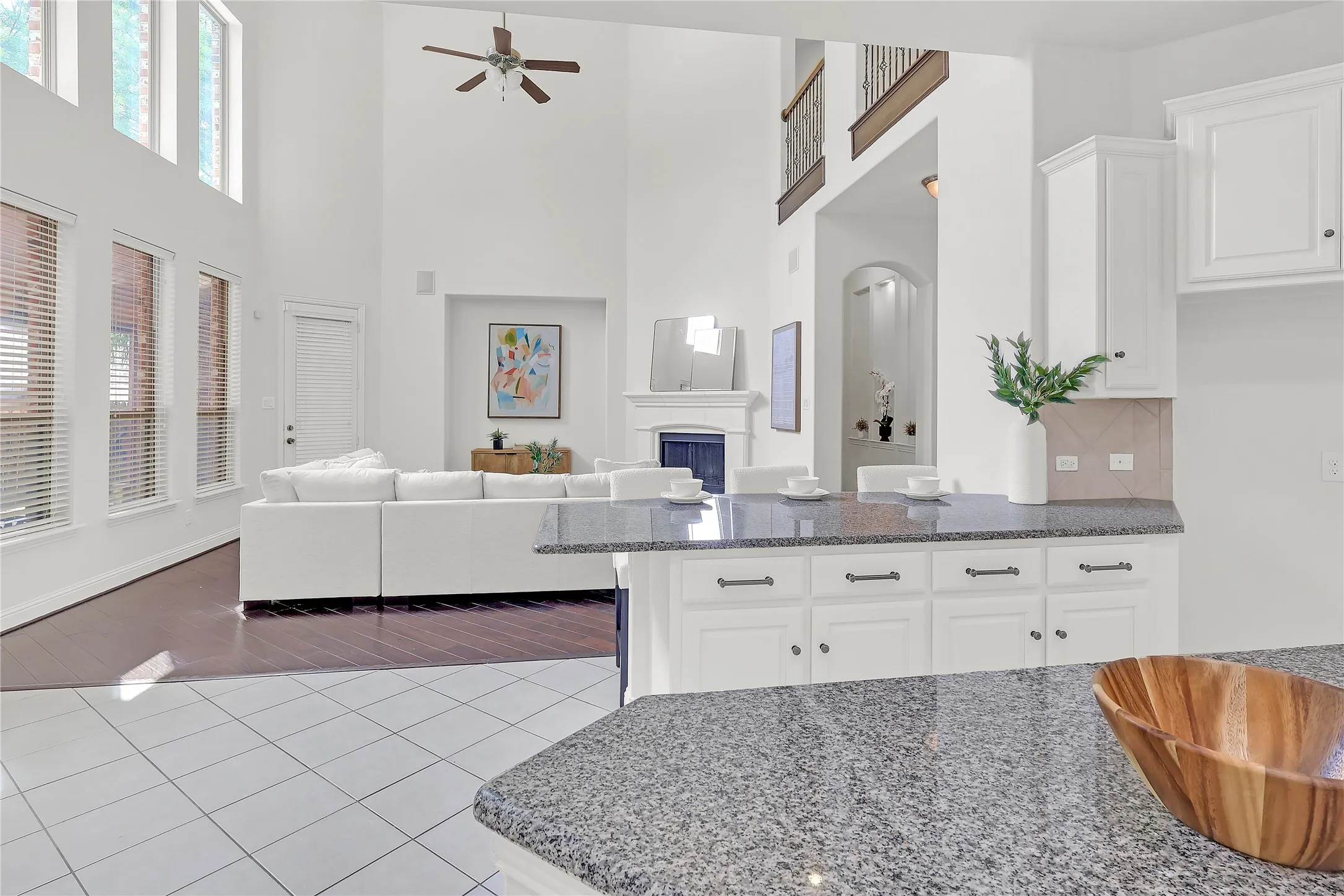 Kitchen featuring dark stone countertops, a towering ceiling, tile patterned floors, ceiling fan, and white cabinetry