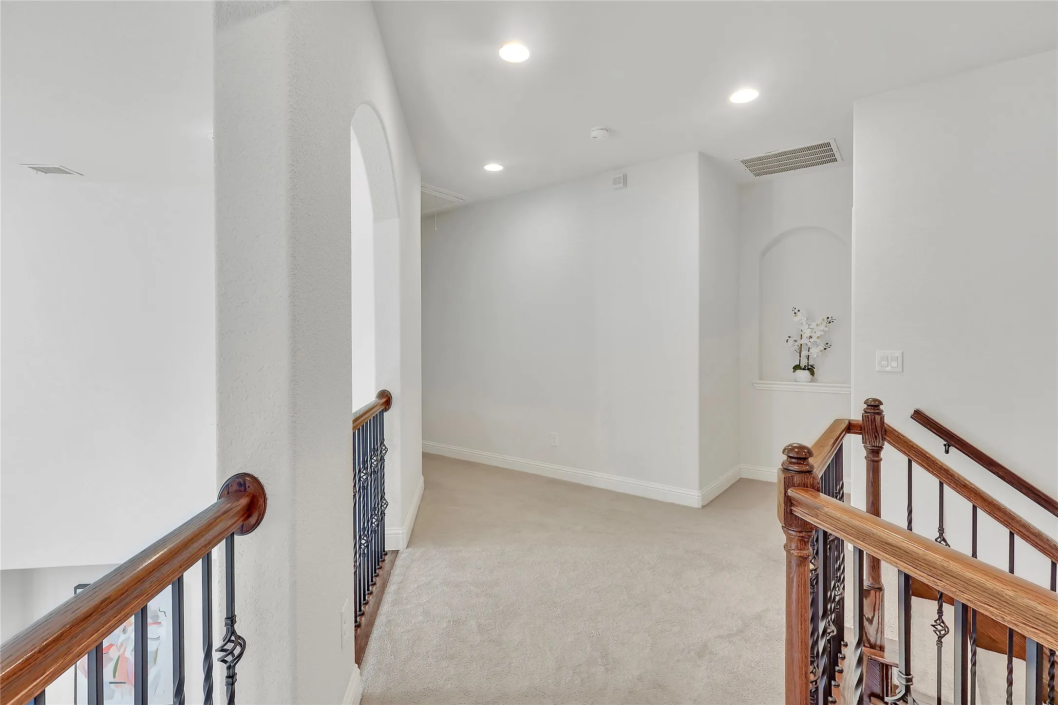 Hall with an upstairs landing, carpet floors, and recessed lighting