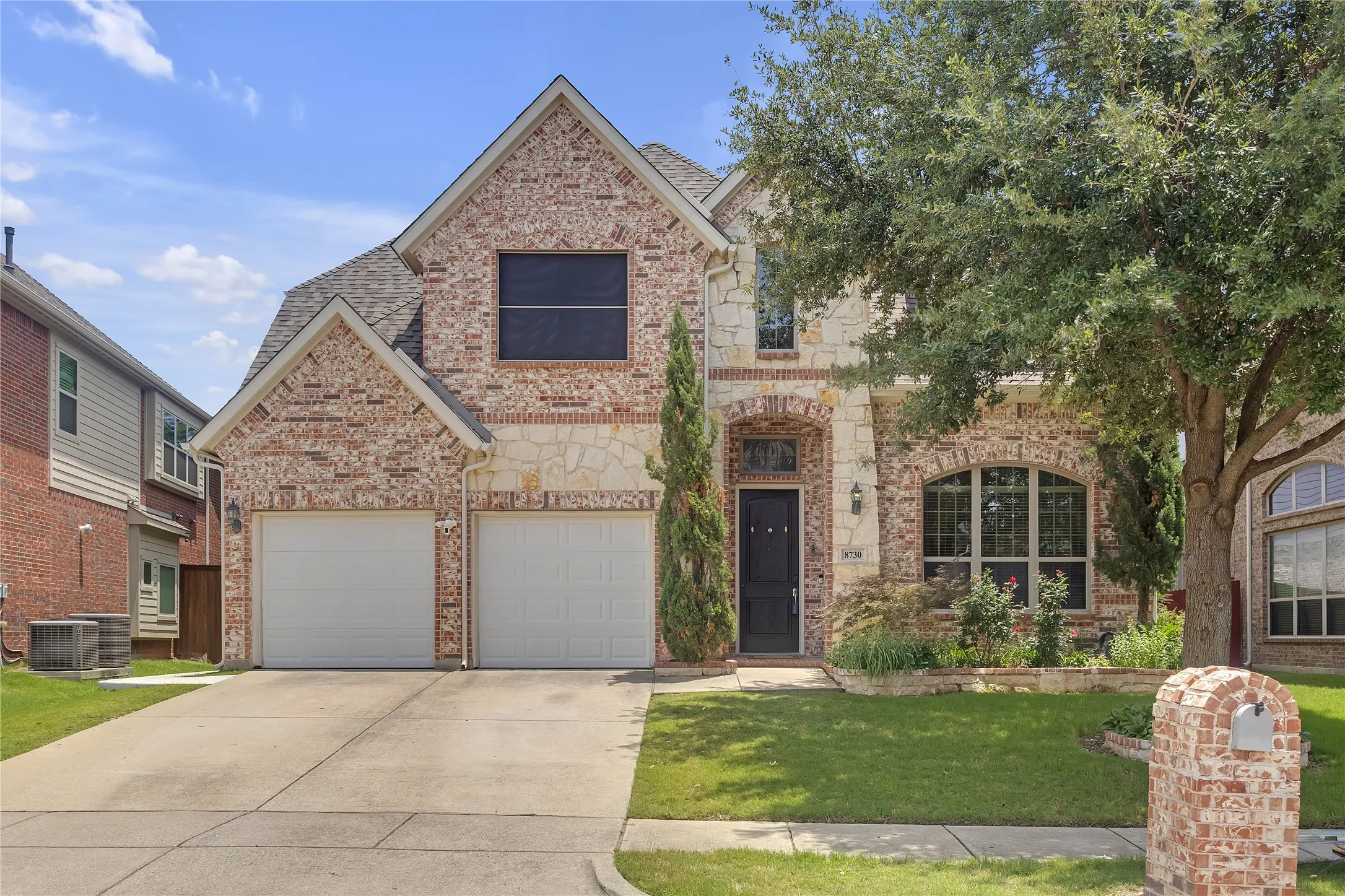 View of front of house featuring concrete driveway, brick siding, a front lawn, a garage, and a shingled roof