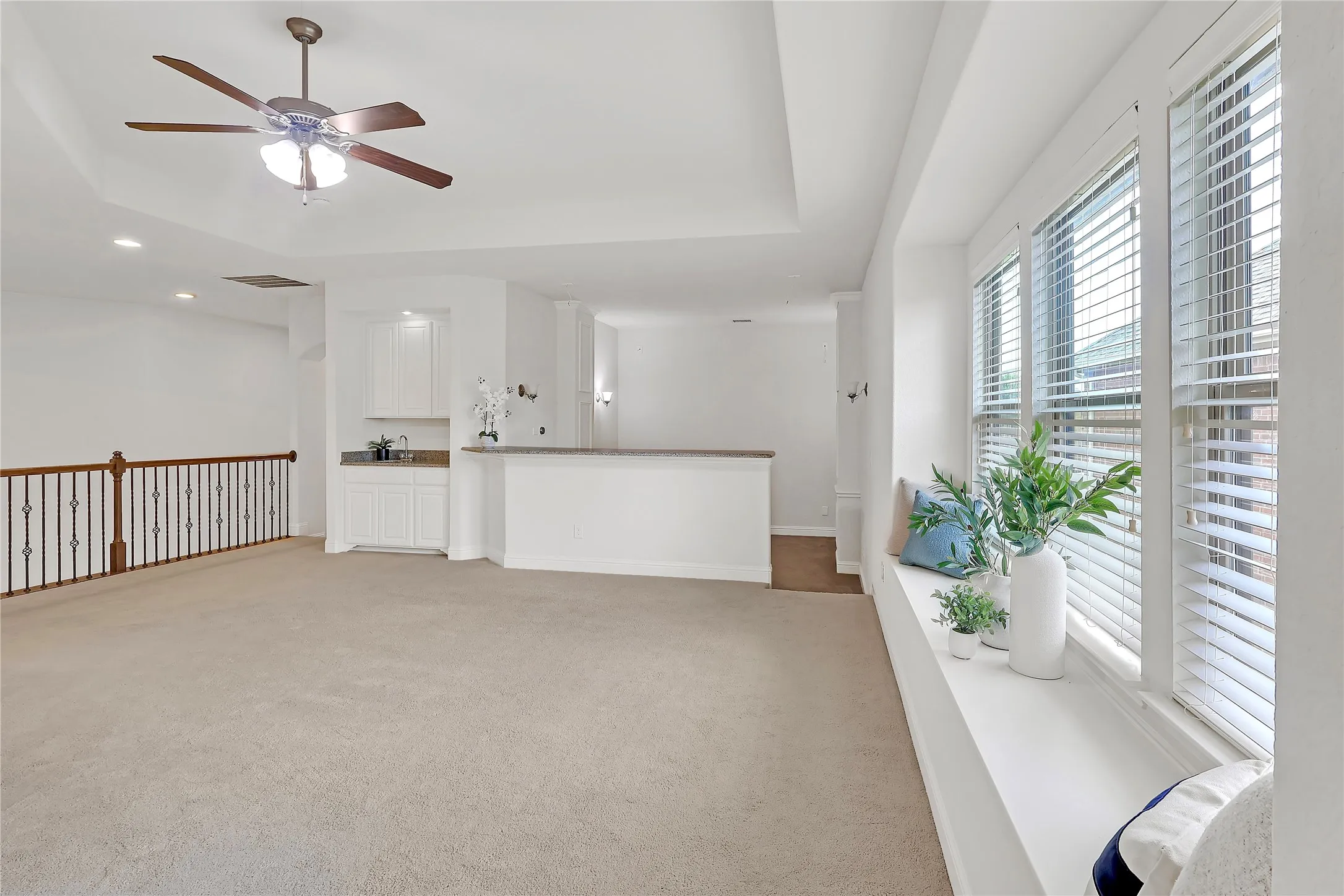 Unfurnished living room with light colored carpet, ceiling fan, a raised ceiling, and recessed lighting