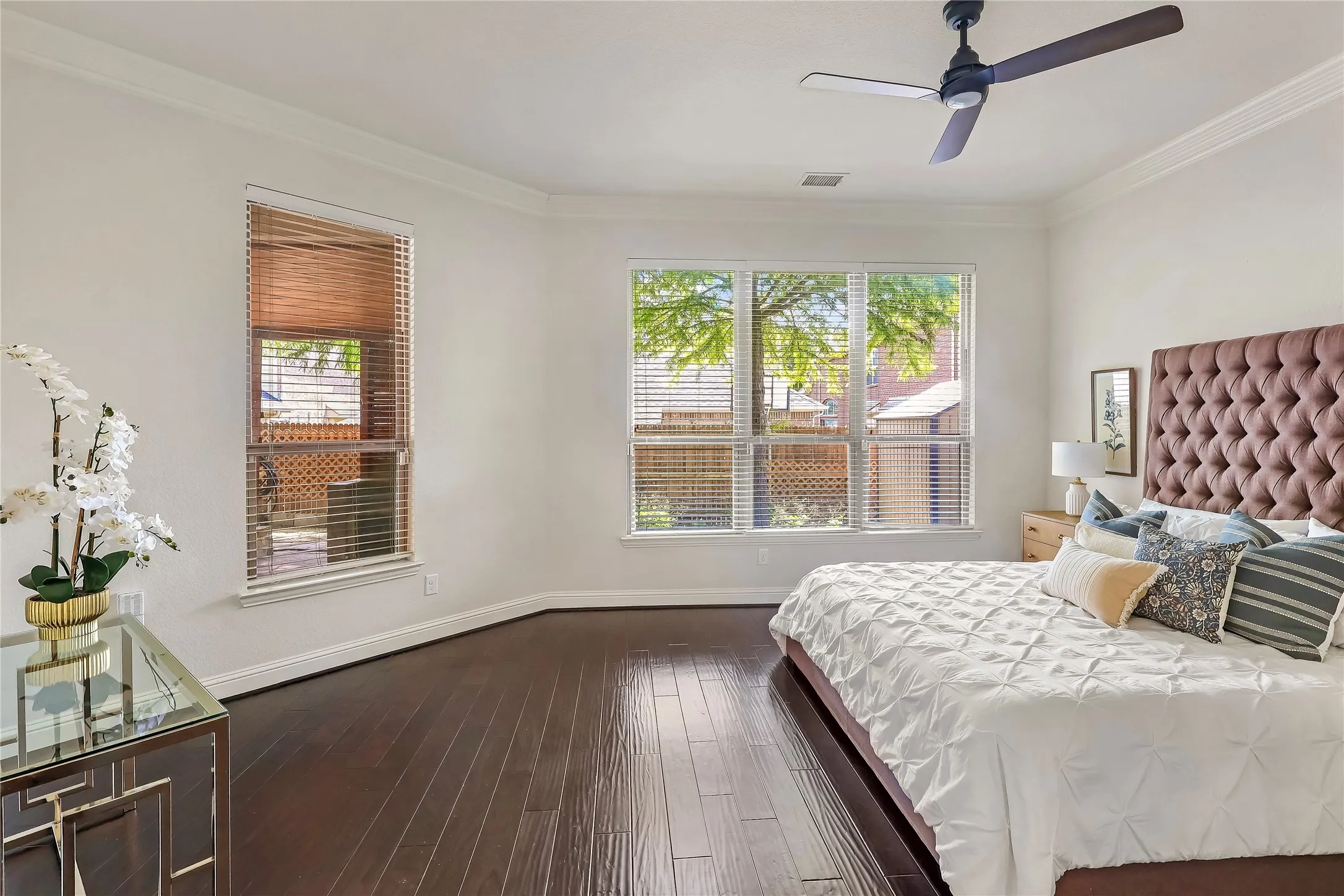 Bedroom with multiple windows, dark wood finished floors, crown molding, and ceiling fan
