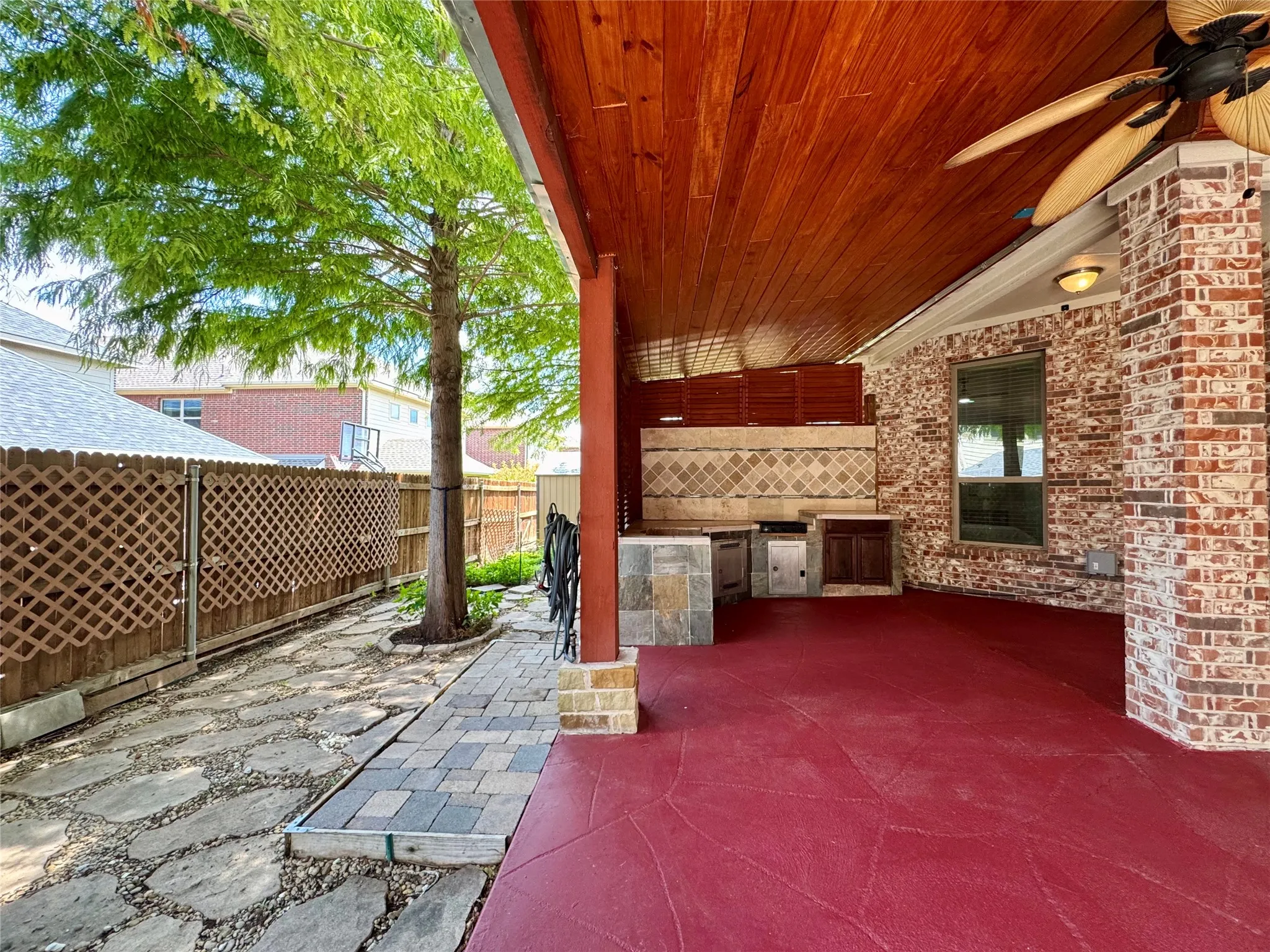 Fenced backyard featuring an outdoor kitchen, a ceiling fan, and a patio area