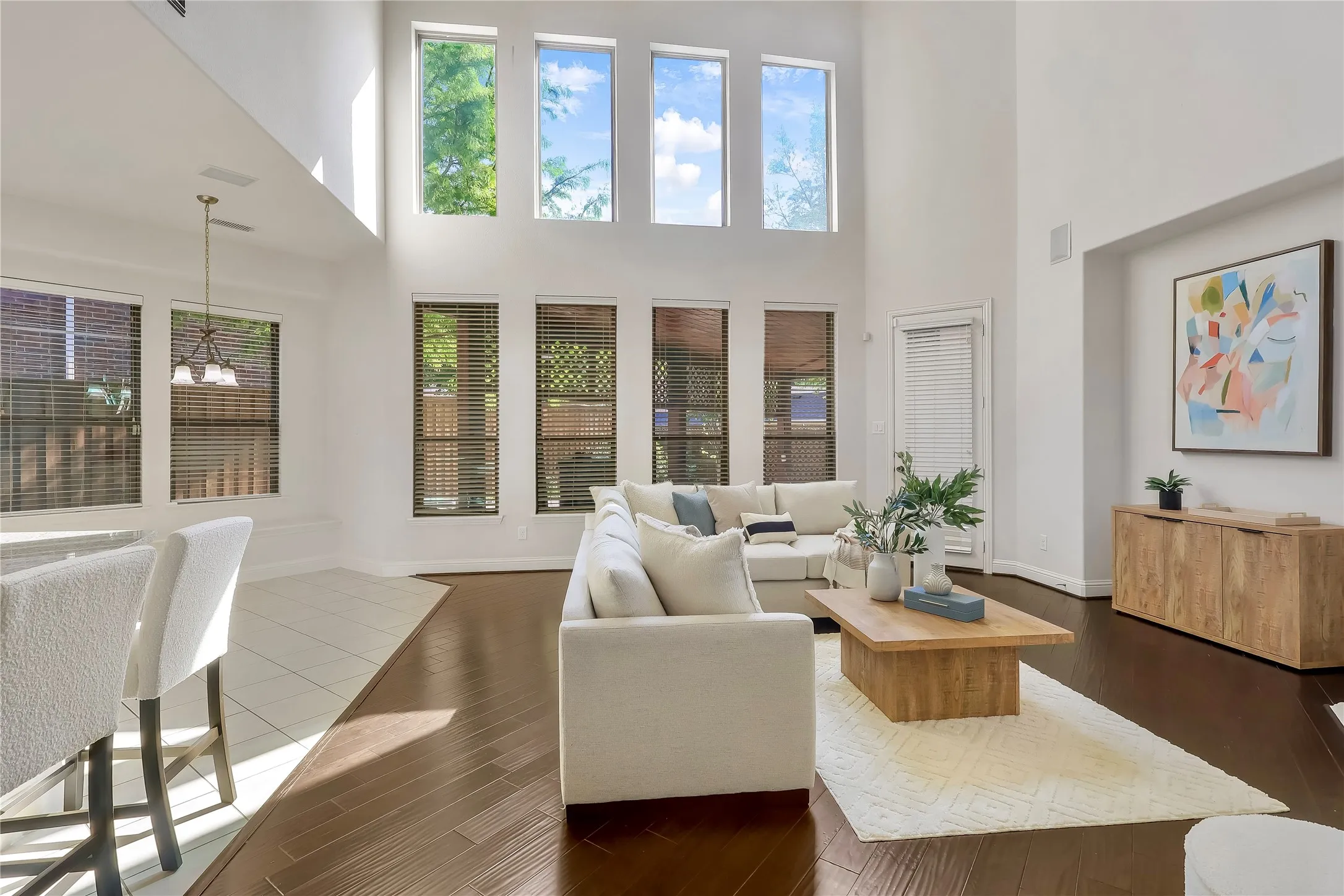 Living area with a high ceiling, a chandelier, and dark wood-style floors