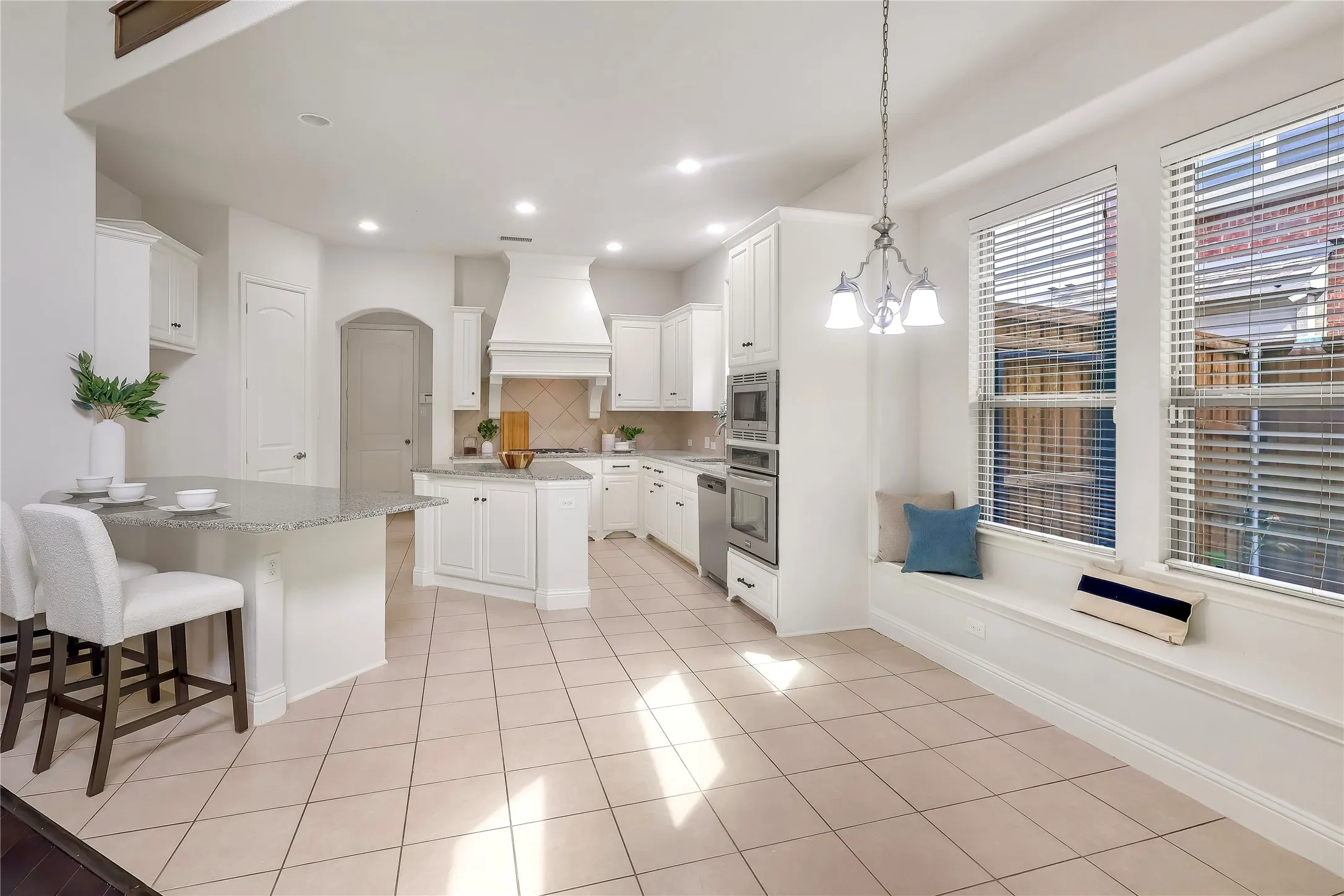 Kitchen with premium range hood, appliances with stainless steel finishes, decorative backsplash, a center island, and arched walkways