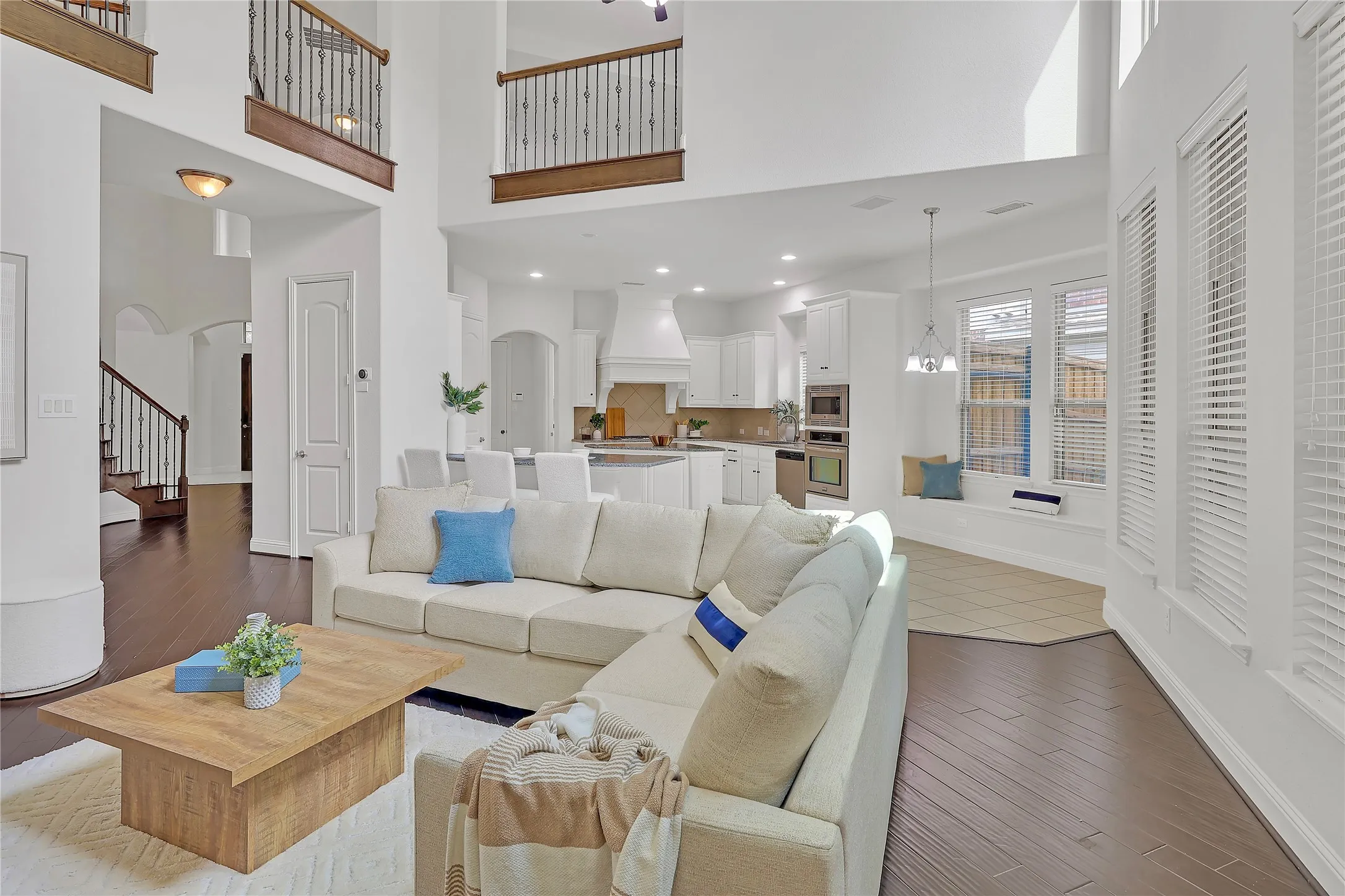 Living area with arched walkways, a high ceiling, wood finished floors, and stairs