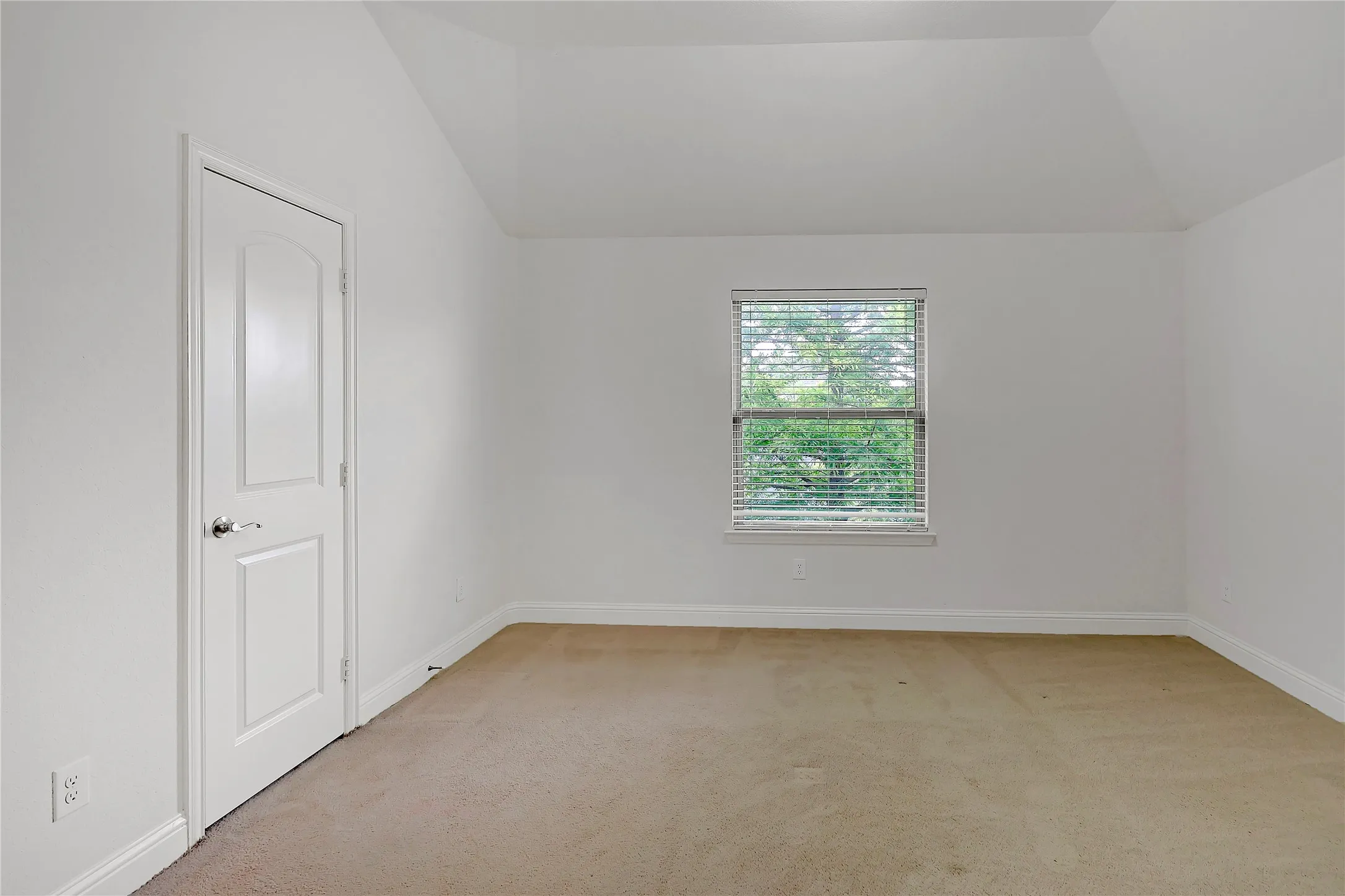 Carpeted spare room featuring lofted ceiling