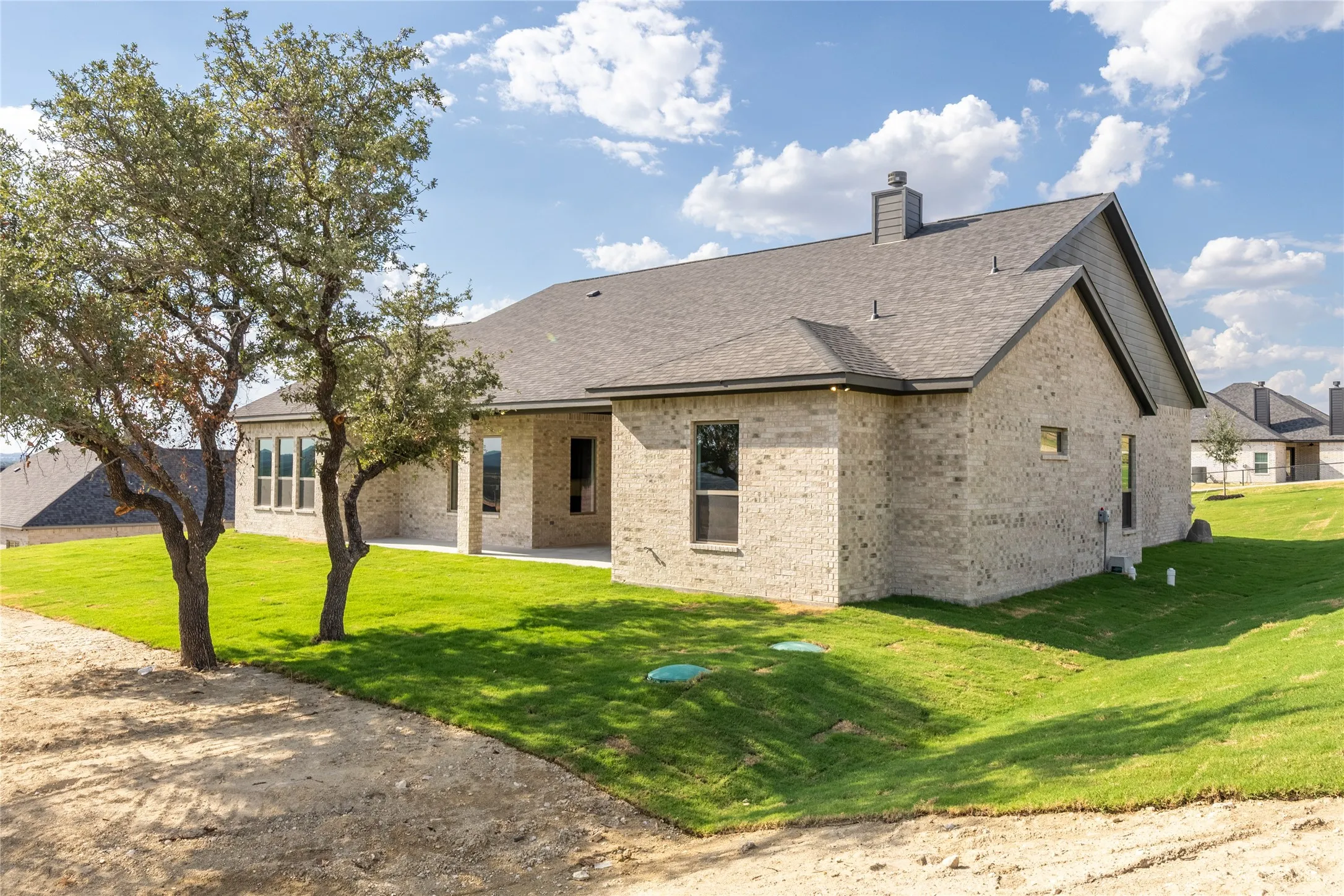 Brick exterior with a dark shingle roof and a covered patio