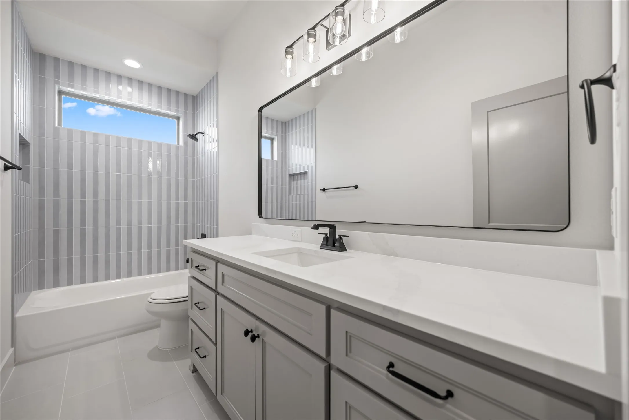 Extended vanity with a light-toned countertop, integrated sink, and black fixtures