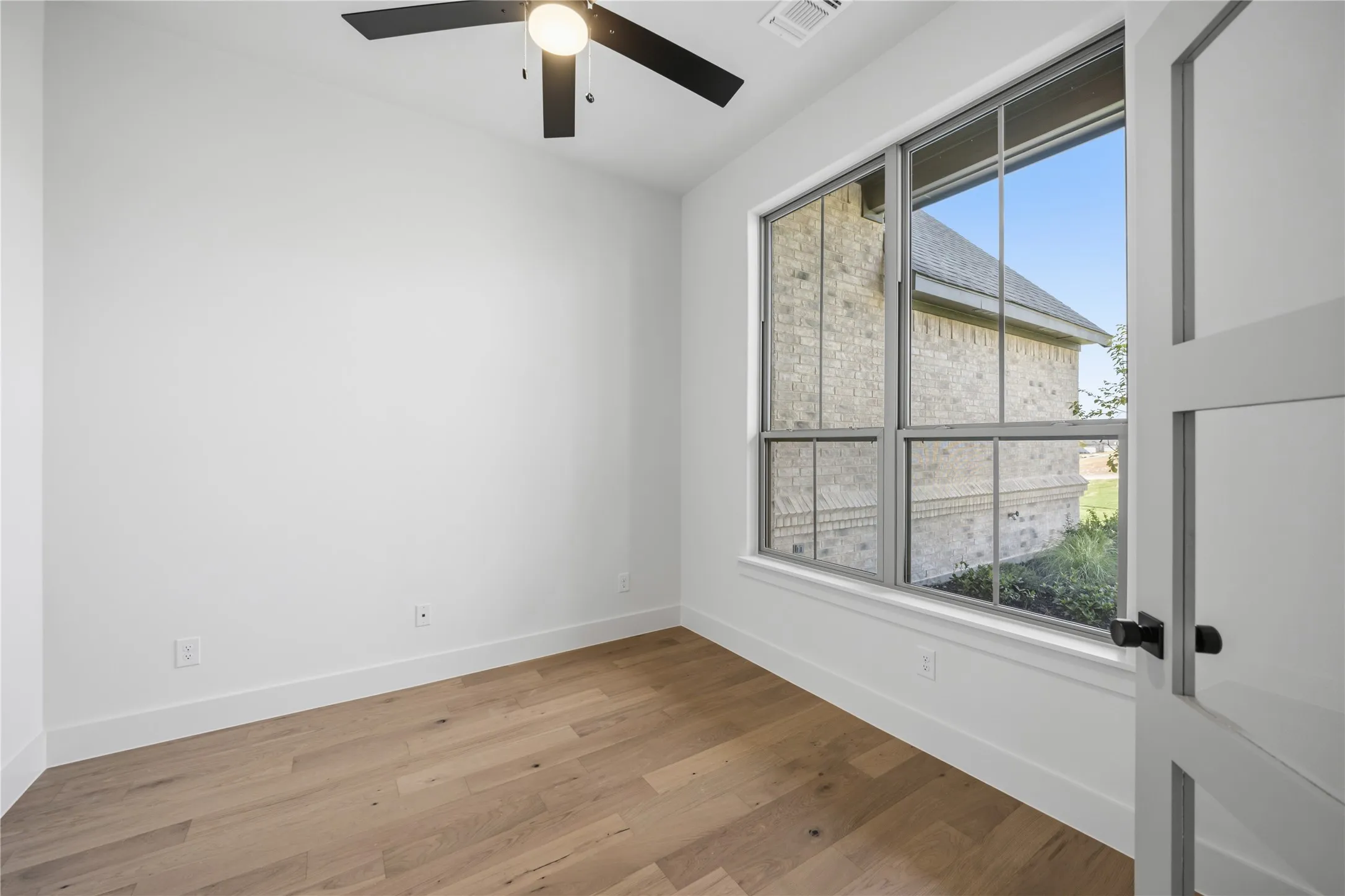 Room featuring wood-finish flooring, a contemporary ceiling fan, and a large multi-pane window