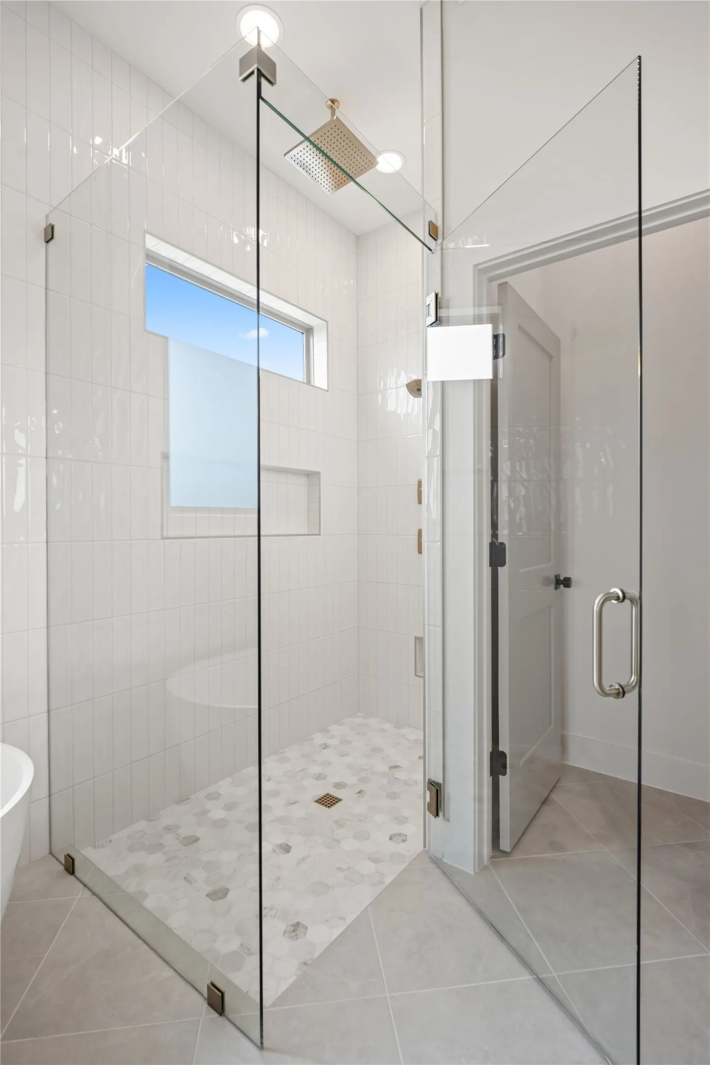 Glass-enclosed shower with a hexagon tile floor, white subway tile walls, and a recessed ceiling light