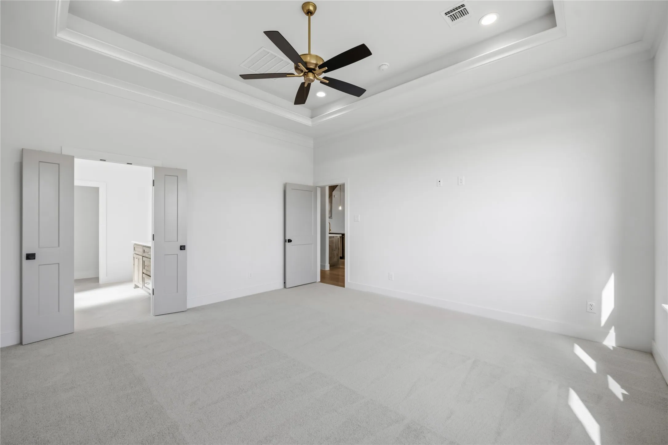 Recessed ceiling with layered crown molding, ceiling fan with integrated lighting, recessed lighting, and light gray carpeting